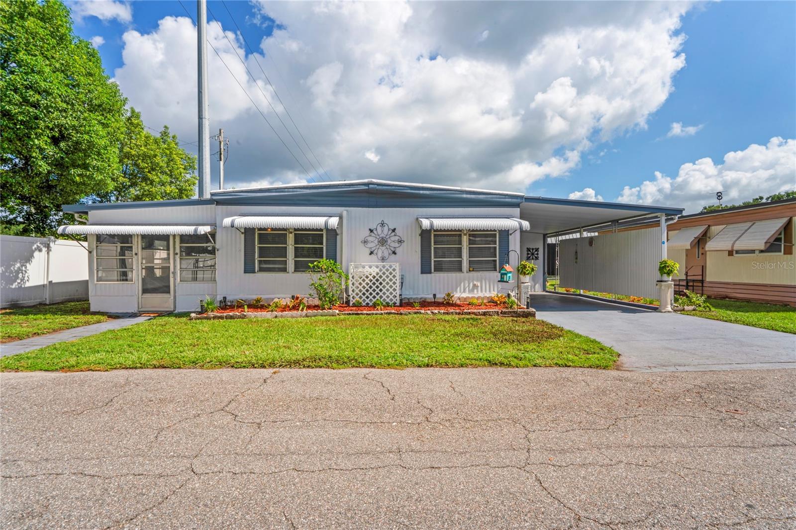 Welcome to this charming furnished move-in ready 2-bedroom, 2-bath home, ideally located at the end of a quiet street in a friendly 55+ community with No land lease and low HOA fees. This lovingly maintained property offers a bright and inviting layout with modern vinyl plank flooring throughout, a cozy electric fireplace in the living room, and a sunny enclosed Florida room perfect for afternoon relaxation or casual evenings.
The kitchen, with its crisp white cabinetry, solid surface countertop, and classic tile backsplash, is designed for your convenience. The cheerful dining nook, filled with natural light, is the perfect spot for your morning coffee. Just off the kitchen, a spacious utility room/workshop includes a full-size laundry and extra storage space.
The primary bedroom, with its dual closets and private vanity area, offers a comfortable retreat. The second bedroom, a versatile space with a built-in desk, can be used for guests, hobbies, or even as a home office, giving you the freedom to personalize your living space. Outside, you'll enjoy a covered back patio surrounded by lush greenery, creating the perfect blend of privacy and curb appeal and a private carport.
The community is beautifully maintained and features a swimming pool, a clubhouse with a billiards area and stage, a community kitchen, and covered shuffleboard courts. Residents enjoy a laid-back lifestyle with organized activities and a strong sense of community.
Whether you're looking for a full-time residence or a winter escape, this well-maintained home offers comfort, peace, convenience, and a warm community atmosphere. This property is a must-see.
