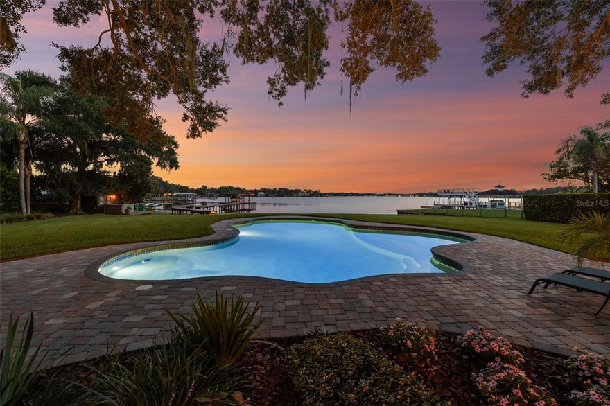 Welcome to 1808 W Bearss Avenue — a once-in-a-lifetime opportunity to own one of the most architecturally distinctive and private lakefront estates in Tampa. With 6 bedrooms, 5.5 bathrooms, and 6,209 sq. ft. of custom-designed living space, this curated residence is set on 1.56 acres with 150 feet of shoreline along the exclusive Lake Magdalene, a 252-acre private ski lake. Only a handful of homes on this lake have the rare combination of architectural scale, acreage, and direct water access, making this an exceedingly uncommon offering in the Tampa luxury market. Inspired by the iconic Southern California designs of Harry Gesner, the A-frame architecture features soaring windows, warm wood tones, and artful finishes throughout. Each room has been thoughtfully curated to flow seamlessly into the next, with hand-selected lighting, textures, and finishes that give the home the feel of a living, breathing art installation. The result is a serene, organic, resort-like experience both inside and out. A brick wall and gated entrance open to a circular driveway, pulling you toward the main home and a 4-car garage connected via porte cochere. The 1,510 Sq. Ft garage offers three individual car bays, with the center bay designed taller for a sprinter van or larger vehicle. In 2022, the second floor was transformed into a fully equipped guest apartment featuring a separate entrance, living room with fireplace, wet bar, mini fridge, and full bathroom—ideal for guests or a mother-in-law suite. Inside the main home, the lake commands attention from the moment you enter. Floor-to-ceiling windows flood the family room with natural light and panoramic water views. A spiral staircase leads to a second-story loft overlooking both the lake and front yard, complete with its own half bath—perfect as an office, creative studio, or lounge. The primary suite is a retreat with lake views, walk-in closet, and spa-inspired ensuite bath with a soaking tub facing the water. Upstairs, two guest rooms feature elevated lofts, one offering its own lakeview perch. The chef’s kitchen boasts Viking appliances (double oven, fridge, gas stove with pot filler), granite counters, double dishwashers, a farmhouse sink, and hidden walk-in pantry, all flowing into an expansive layout ideal for entertaining. Just off the kitchen, the formal living room offers an inviting retreat beneath exposed wood beams and vaulted ceilings. Rich hardwood floors and layered lighting create a cozy-yet-elevated ambiance. The dry bar and wine fridge make this space ideal for entertaining. Step outside and you’re transported to your own private lakeside sanctuary. The resort-style backyard unfolds with a sparkling open-air pool, Azek premium deck, and uninterrupted, panoramic views of Lake Magdalene. Swim beneath the oaks, sunbathe with wide-open water as your backdrop, or stroll directly from your private beach into the lake—no seawalls, no obstructions, just pure shoreline access. Immaculate tropical landscaping and vibrant gardens create a sense of natural privacy, while a covered boat dock with lift and sunset-view hot tub deck provide the ultimate in waterfront luxury. Additional features include a media room with new carpet, formal dining with organic leaf wallpaper, an outdoor shower, fenced dog run, and a 200-gallon propane tank. All just minutes from Carrollwood Day School, Whole Foods, fine dining, and Dale Mabry—offering seclusion, design, and convenience in one unforgettable package.