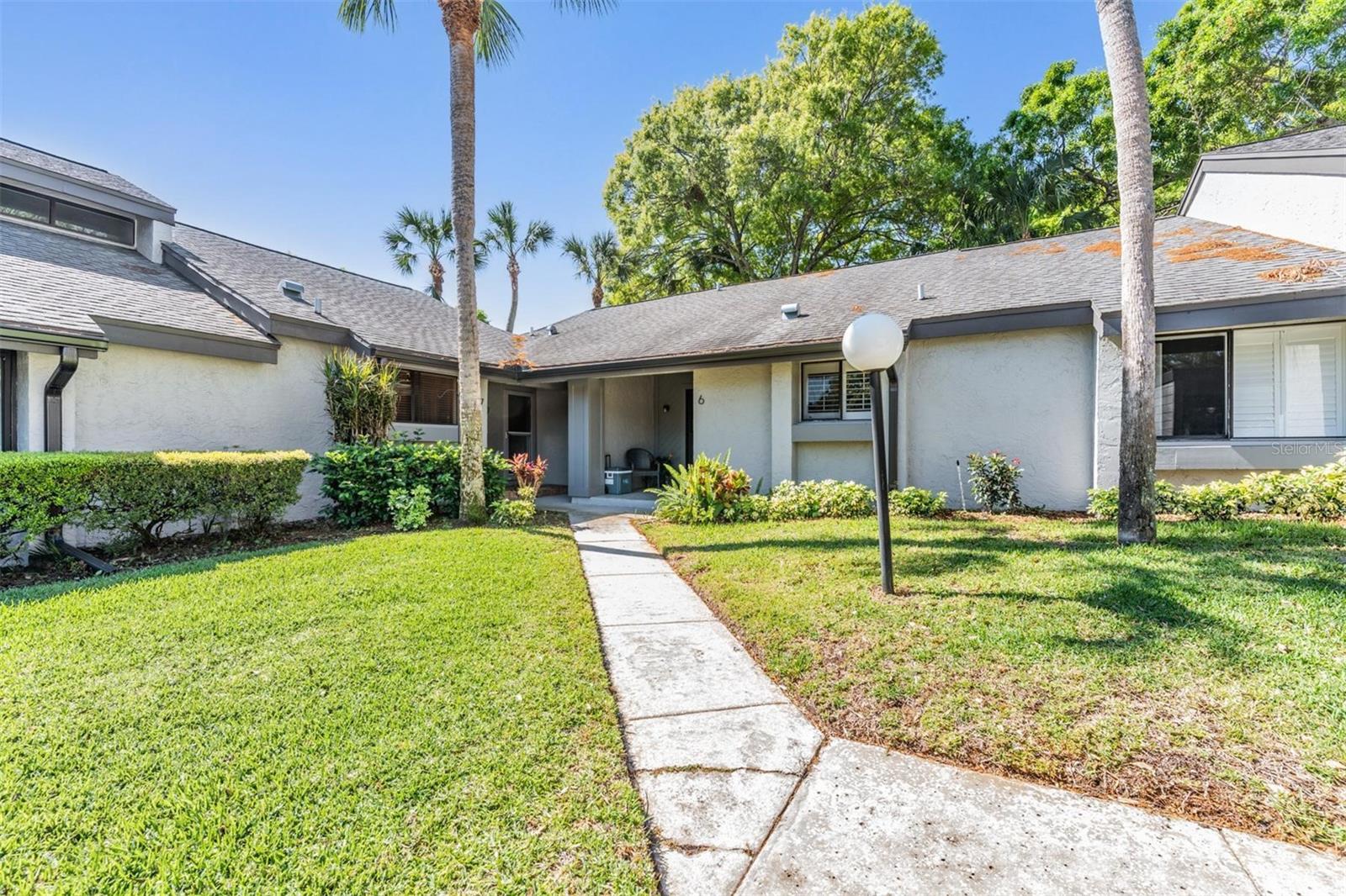Turn-Key Rental. Welcome to resort-style living in this well-maintained 2-bedroom, 1.5-bath villa, nestled in a vibrant waterfront community in Tarpon Springs, Florida! From the covered front porch, step into the bright and inviting layout. The entryway features a spacious closet and flows into the dining area, which sits just off the kitchen and overlooks the living room. Vaulted ceilings, a cozy fireplace, and sliding glass doors open to the patio, offering a peaceful retreat with views of the green space and tennis courts. The kitchen is well-equipped with stainless steel appliances, granite countertops, plenty of cabinet space, a pantry, tile flooring and the opening to the dining area makes it ideal for entertaining. The spacious primary bedroom boasts large corner windows that fill the space with natural light, two closets, and an ensuite half bath featuring a large vanity and a connecting door to the full bathroom. The second bedroom, also ideal as an office or den, offers tile flooring, plantation shutters, a built-in bookshelf, and a pass-through to the kitchen. Additional highlights include an in-unit washer/dryer closet, plantation shutters throughout, covered parking, and a nearby storage closet for bikes, seasonal décor, or extra belongings. Just a short walk from the pool and tennis courts, this villa is part of a friendly, active community featuring a heated pool, clubhouse, fitness center, tennis and pickleball courts, shuffleboard, a fishing pier, and a lakeside BBQ area. Private boat slips are available for lease, and low HOA fees cover water, sewer, trash, and exterior maintenance. All of this is located in a no-flood zone, just minutes from the historic Tarpon Springs Sponge Docks, top-rated restaurants, shopping, beaches, parks, and golf courses. Come see for yourself—schedule your private showing today!