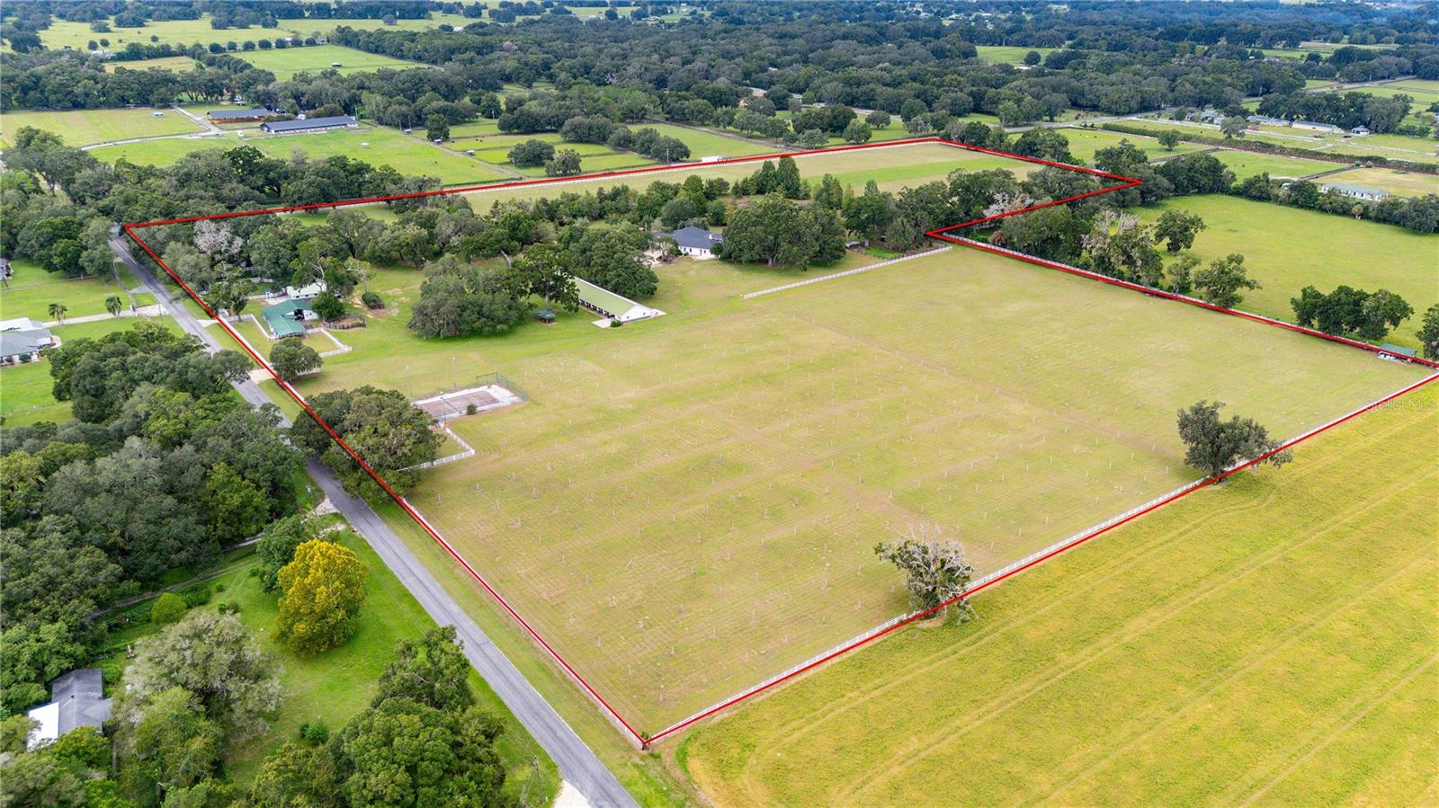 Welcome to a stunning 40+ acre estate right in the heart of Ocala’s horse country formerly known as Fiddle Leaf Farm. This gorgeous property was once used as a beautiful blueberry farm surrounded by vinyl fencing and featuring two separate entrances, the estate ensures privacy and security. The main residence features 4 bedrooms and 3.5 baths, including a custom wine room, a screened-in pool, a master suite with private access to the pool, an upstairs flex room perfect for storage or hobbies, and 3 car garage! The home features new exterior and interior paint. Don't forget the 2 barns with grooms' quarters, 20 horse stalls, a private tennis court, and beautiful acreage with potential for even more! Whether you are looking for a working farm for horses and livestock or a secluded compound has it all. Schedule your showing today!