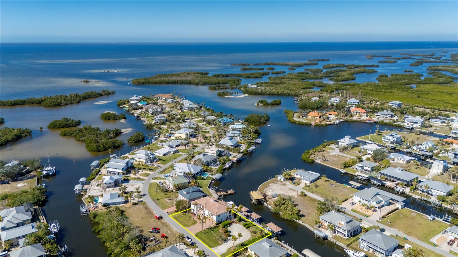 Relax and indulge in the quintessential Waterfront Florida lifestyle, seamlessly blending indoor and outdoor living spaces. This Spectacular Custom Designed and Built 2-Story Pool Estate Home Featuring 5 bedrooms/4 bathrooms and 1/2 bath, oversized 3 Car Garage with 2 large storage closets and is situated on two lots. Located in the Graceful community of Pirate Harbor with 200ft on the Water, and 182ft of Boat Dockage, this is the Perfect Home for the Boating Enthusiast, with 3 Boat Houses with Tile Roofs and they are equipped with a 7,000lb lift, a 10,000lb lift and a 17,000lb lift, and a separate Granite top Fish Cleaning Station, along with a Kayak Launch, there 62ft of Free Span Dock space for Larger Boats with a separate Guest Boat 30/50 amp power tower, giving you and your Guests Direct access to Charlotte Harbor, Pine Island Sound and onto the Gulf of Mexico for World Class Boating and Fishing. This Impressive Home offers Design, Attention to Detail, Function and Quality from the ground up. The Upper Level living space showcases soaring ceilings, Gas Fireplace, Open concept space flows seamlessly into the beautiful Dining Area, to the Gourmet kitchen featuring two breakfast bars, a walk-in pantry, 2 built-in wall ovens, Center Island with a 5 Burner Gas Cooktop, abundant Stone countertops for easy meal prep and entertaining space, Screened Patio runs the length of the upper floor giving you Waterfront Views and more Entertaining area. The Split Floor Plan allows for a Private Primary Suite featuring Tray Ceilings, a luxurious walk-in shower, a soaking tub, Dual Vanities and His and Her’s walk-in closets, along with access to the screened Balcony overlooking the Water, what a nice way to start your day and end your day, Guest Powder Room, two Guest Rooms with Jack and Jill Bath, and a Guest En-suite with Private access to the Balcony so that they can also take in the Waterfront views, 2 Stop Elevator, abundant storage throughout, Laundry room with Utility Sink, Stone countertops and additional cabinetry. On the Ground Floor you will find the 5th Bedroom, Ideal for Entertaining and/or Mother In-Law/Guest Suite with full Bath and Kitchen and Murphy Bed, with Separate Outside entrance and access to the climate controlled Breezeway/Gym area with fully retractable Sliding Doors opening up to the Spacious Covered Patio overlooking the Infinity Edge Pool and Spa, allowing this space to extend your Living Space. There is a secure climate controlled Tackle room with rod holders, custom cabinetry and access to the Pool and Deck area. Whole house Tradewinds LP Generator in the Garage. The Additional lot offers parking for your RV and all your Toys. This Amazing and one of kind Home truly represents the Florida Waterfront Lifestyle and has all the Luxury Appointments you Desire, offering the very Best in Waterfront Living, we Invite you for a Private Tour of your new Waterfront Estate Home. The Pirate Harbor Community is just a Short Drive to Punta Gorda, Beautiful Burnt Store Marina, Pine Island, St. James City, Matlacha, Cape Coral, Golf,