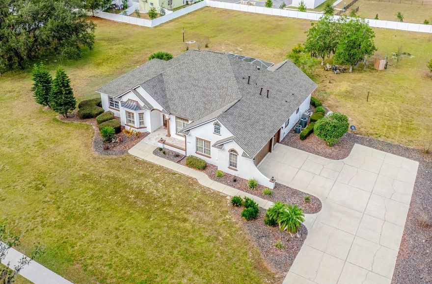 One or more photo(s) has been virtually staged. Ask about a lender provided RATE BUY-DOWN CREDIT on this home! ***RARE OPPORTUNITY FOR 2+ ACRES ADJACENT TO THE VILLAGES!*** Set on two spacious lots totaling 2.28 ACRES, this one-of-a-kind ESTATE HOME in Wildwood delivers the rare combination of luxury, land, and freedom – NO HOA, golf-cart friendly, and just 2.2 miles from Brownwood Paddock Square in The Villages! Formerly an executive model home, the property has been fully REMODELED and thoughtfully UPGRADED, offering a MOVE-IN READY lifestyle with room to EXPAND, build, or relax, unwind and enjoy the space around you. ***MAJOR UPDATES INCLUDE: a BRAND NEW ROOF (2025), 2 NEW TRANE A/C SYSTEMS (2025), a NEW WATER HEATER (2025), FRESH INTERIOR & EXTERIOR PAINT, UPDATED LANDSCAPING, and NEW FENCING on the back and sides for added privacy. Every big-ticket item has already been handled – so you can focus on living! Curb appeal is immediate, with a side-facing OVERSIZED 2-CAR + GOLF CART garage, manicured landscaping, and the presence that only a former model home can offer. Inside, over 3,400 square feet of curated living space unfolds with high-end finishes, CERAMIC TILE and LUXURY VINYL PLANK FLOORING throughout, flexible formal areas, and an open, inviting family room that flows seamlessly into a light-filled breakfast nook and a timeless kitchen with a modern edge – perfect for any style! The home chef’s dream kitchen features sleek CULTURED GRANITE COUNTERTOPS, an ISLAND with prep sink, and NEW GE CAFE APPLIANCES, ideally suited for both everyday living and entertaining with ease. The sprawling OWNER’ SUITE is a true retreat, privately tucked into its own wing of the home. French doors open directly to the lanai – sip your morning coffee – while the suite itself boasts a massive CUSTOM CLOSET with built-in desk and a spa-inspired en-suite bath with dual sinks, lighted mirrors, soaking tub, and an oversized walk-in shower. Guest bedrooms are located on the opposite side of the home with a beautifully updated full bath between them, delivering privacy and comfort for everyone. Outdoor living truly shines here - an expansive COVERED LANAI with a BRAND NEW OUTDOOR KITCHEN  – complete with stone finishes, stainless hood, gas range, sink, and built-in beverage refrigerator – overlooks the HEATED POOL and seemingly endless backyard. A convenient FULL POOL BATH opens directly to the lanai, making entertaining effortless with the opportunity to add a door and create an en-suite to the neighboring bedroom. Mature trees create a tranquil, private setting that feels worlds away, yet keeps you minutes from a variety of shopping, dining, and entertainment. The second attached lot is fully buildable, offering endless possibilities – add a detached garage, workshop, guest home, or create a multi-generational setup. To further enhance privacy and long-term landscaping value, the sellers have recently planted a combination of fast-growing privacy trees along the property borders, including Leyland Cypress and Southern Red Cedar. These trees are widely known for their rapid growth rate and dense evergreen foliage . With no HOA restrictions, space for toys, hobbies, or future expansion, and proximity to The Villages, this property stands in a category all its own. This is not just a home, it’s a lifestyle upgrade! Call today to schedule your tour and let us say WELCOME HOME! ***Seller may consider buyer concessions if made in an offer***