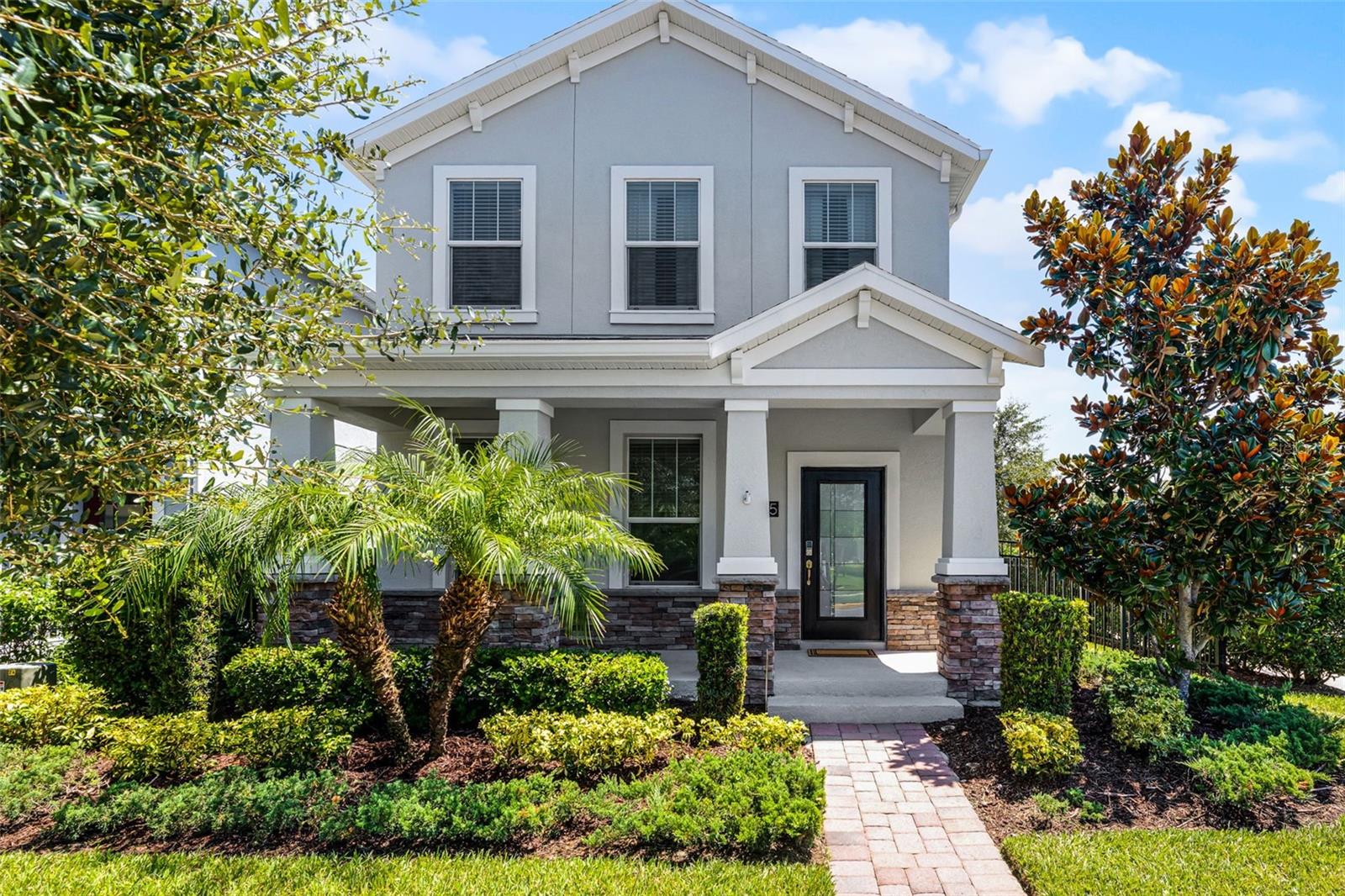 Discover timeless style and modern design in this beautifully maintained two-story home on a fenced corner lot in the highly sought-after Storey Park community in Lake Nona! Built in 2018, this 3-bedroom, 2.5-bathroom home features a stone-accented exterior, a charming front porch, and fresh exterior paint that enhances its inviting curb appeal. Step through the front door into a spacious foyer that sets the tone for the home's open and welcoming layout, with tile floors throughout the entire first floor, creating a seamless flow. The kitchen is a standout, offering quartz countertops, rich wood cabinetry, a tile backsplash, closet pantry, reverse osmosis system for purified drinking water, and a counter-height breakfast bar—perfect for entertaining and everyday meals. Just off the kitchen are the dining area and expansive family room, with a flex room at the front of the home ideal for a home office or second living space, adjacent to a stylish half bath with a modern barn door. Abundant windows throughout the main living areas flood the space with natural light, enhancing the open, airy feel of the home. Laminate wood flooring extends from the staircase and continues throughout the entire second floor, including all bedrooms and the hallway. The spacious primary suite includes a ceiling fan, a large walk-in closet with barn door, and an en-suite bathroom with dual sink vanity, garden tub, and glass-enclosed walk-in shower. Two additional bedrooms also feature ceiling fans and share a well-appointed second full bathroom. One of the bedrooms includes an oversized walk-in-closet - large enough to double as a playroom, hobby space, or extra storage. A bright and functional upstairs laundry room includes a window for natural light and built-in shelving for storage and organization. Additional features include a whole-house water softener system, adding improved water quality and protection for your plumbing and appliances. Step outside to your private backyard oasis, where a paver patio with a wood pergola creates the perfect setting for outdoor relaxation or entertaining. The detached 2-car garage, accessed from a rear alley, connects to the home via the patio and leads into a convenient mud room with built-in drop zone—ideal for daily organization and storage. Enjoy a vibrant lifestyle in Storey Park, offering resort-style amenities including a pool, clubhouse, fitness center, dog park, playgrounds, and scenic walking trails. Located in Orlando’s Lake Nona area, close to Medical City, top-rated schools, major highways, shopping, dining, and Orlando International Airport—this home blends comfort, function, and location in one of Central Florida’s most desirable communities.