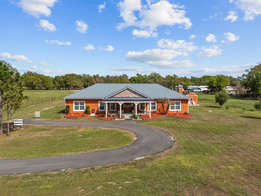 Country with Class or County Chic—either way, this custom 2017 home delivers both style and serenity on 5.43 acres just outside Bartow. Enjoy the peace of country living while staying conveniently close to Bartow, Winter Haven, Lakeland, and Lake Wales.
Step through the front door and you’re greeted by wide-plank custom wood flooring that flows throughout much of the home. The spacious living room features a stunning floor-to-ceiling stone wood-burning fireplace, creating a warm and inviting focal point. Overlooking the living area is a gourmet kitchen complete with a large island, stainless steel appliances, vented hood, pot filler, custom mosaic backsplash, and an additional built-in oven. A generous pantry and laundry room sit just off the kitchen for added convenience. The adjoining breakfast nook and formal dining area offer plenty of room for gatherings. The home features three large bedrooms, including a luxurious primary suite with a tray ceiling, oversized walk-in closet, and French doors leading to the screened patio. The primary bathroom includes dual sinks with a center vanity, a private water closet, and a walk-in shower equipped with multiple showerheads. The second and third bedrooms share a spacious Jack-and-Jill bathroom, each with its own private sink and direct access to the shared tub/shower and toilet area. One of the standout features of this home is the expansive screened-in patio, accessible through three sets of French doors. This impressive outdoor living space overlooks the back acreage and serves as a true extension of the home. Beyond the patio, the property continues to impress with a powered shed currently used as an extra bedroom, a charming greenhouse constructed from salvaged windows, and a large chicken coop ready for your flock. A substantial enclosed barn with an attached lean-to and two stables provides ample room for horses, livestock, equipment, or recreational vehicles. A nearby tack shed adds even more functionality. With room to roam, grow, and create the lifestyle you’ve been dreaming of, this property offers a rare blend of comfort, craftsmanship, and country charm.