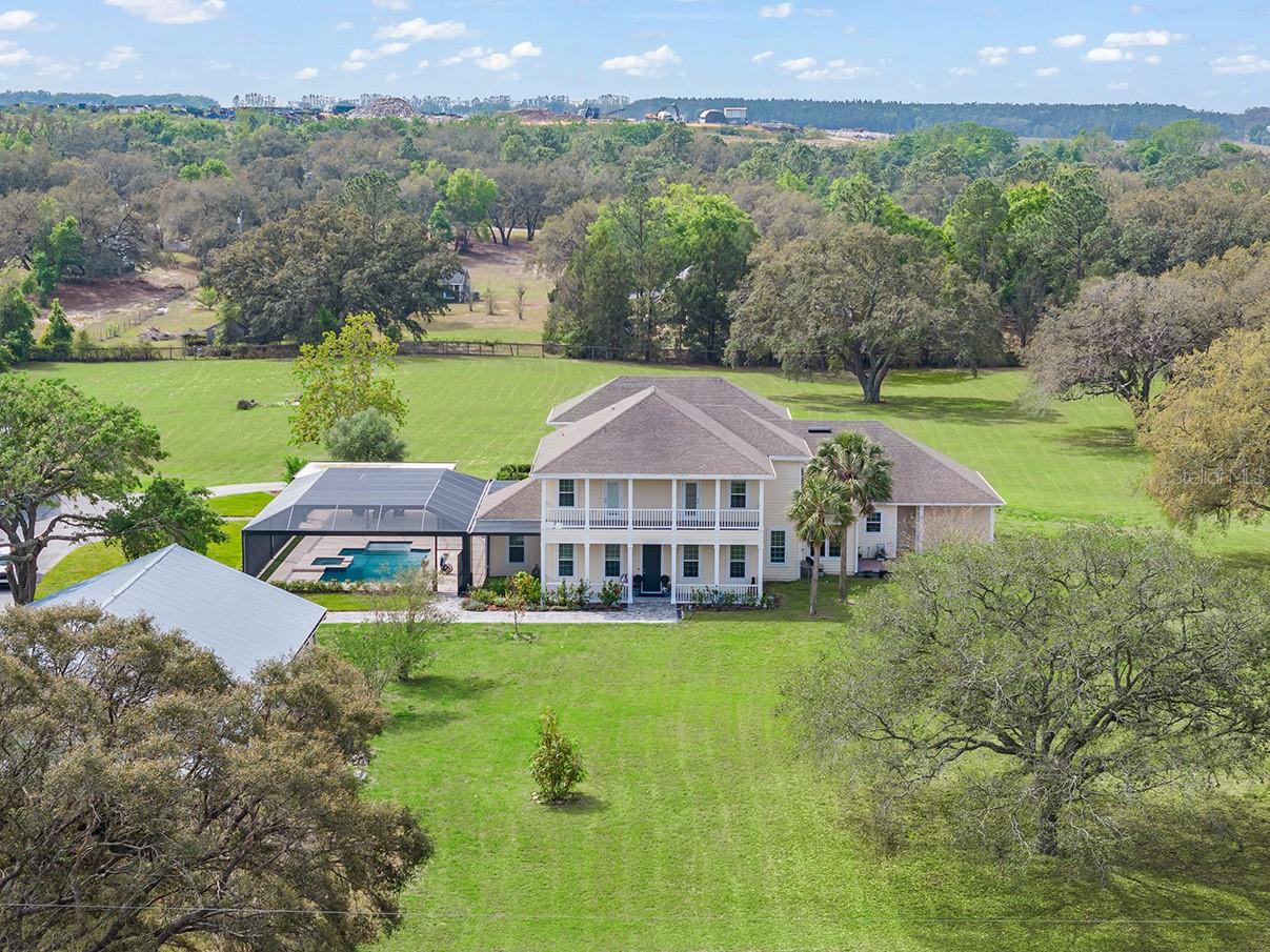 Remarkable opportunity to own a sprawling equestrian-friendly privately gated estate with a newer custom-built 5-bedroom luxury home, detached 5-stall horse barn with studio apartment with kitchen, plus a separate 5-bay RV or car collector’s garage building – all on 5.11 acres within the Lake Avalon Rural Settlement. Escape from the hustle to a country retreat still minutes from Hamlin Town Center and Winter Garden Village but offering a quiet refuge with room to roam. The grand residence was extensively remodeled and expanded to add a soaring primary retreat with second-floor loft, primary bath, catering kitchen and pantry, breakfast nook, Florida room, renovated pool and spa with sun shelf and added screen enclosure and Travertine decking, putting green, plus additional 3-car attached garage. Reimaged with additional living spaces and a functional floor plan built for families of any size. The expansive breakfast nook and beverage bar ensures there’s ample room for everyday gatherings. The primary bedroom is downstairs plus a junior master suite. The master loft is a perfect space for a home office, gym, or extra closet space. Upstairs are three additional bedrooms, all ensuite, and a bonus room. A separate detached apartment is located off the stable for guests or a home office. The 5-stall barn and tack room are perfectly suited for on-site horse boarding. The detached collector’s garage is generous in size and built to accommodate cars, boats, or trailers – or a spectacular workshop. The Lake Avalon Rural Settlement ensures quality of life is preserved in this area by restricting growth and protecting the community’s legacy; meaning, rest assured this area will remain mostly as it is now and not swallowed by subdivisions. Come experience a life uninterrupted and spread out with room for gardening, chickens, livestock, horses, or play – all within a short drive to the shopping and restaurants of Winter Garden Village. Enjoy easy access to the SR 429 Expressway providing a direct route to downtown Orlando and beyond.