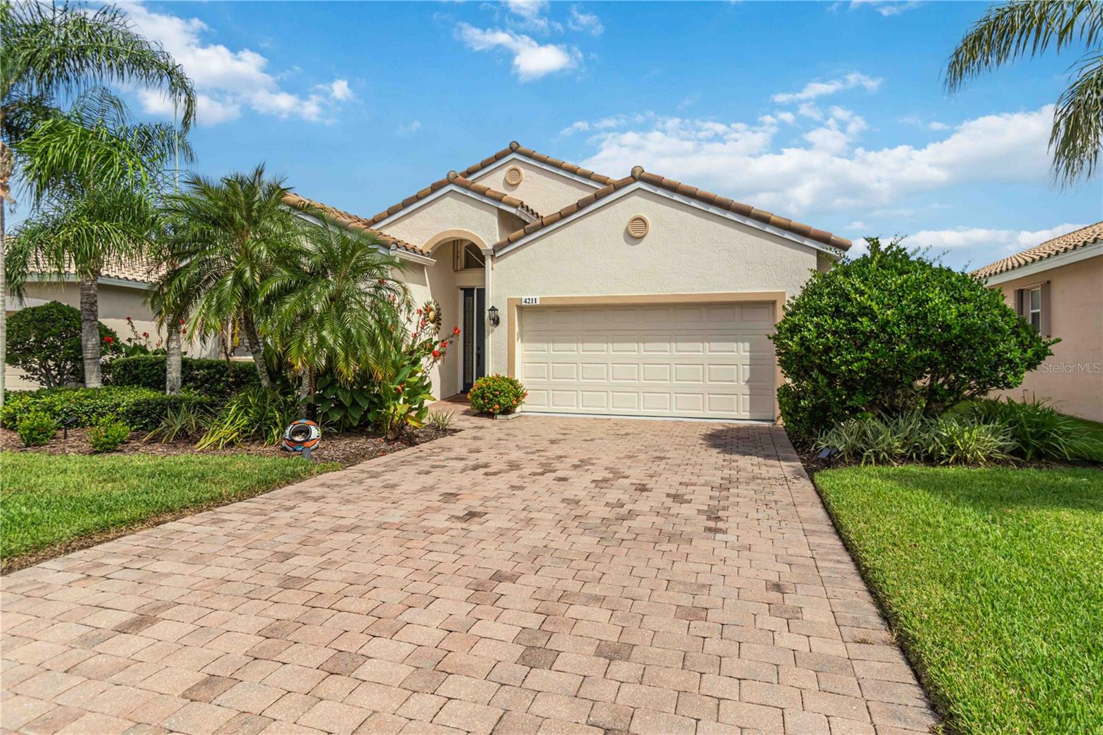 Welcome to this beautifully appointed home in the highly sought-after Cascades at Sarasota, a premier gated 55+ community offering resort-style amenities and true maintenance-free living. From the moment you arrive, the home’s charm is evident with its hurricane-rated glass entry door framed by elegant side and arched transom windows. Accordion shutters on all windows and sliders provide peace of mind with a design that is quick, convenient, and effortless to use. An extended screened lanai, completed in 2022 creates a wonderful outdoor retreat for entertaining or simply relaxing while enjoying the tranquil lake view with shaded Northern exposure. Inside, the home showcases a harmonious blend of style and comfort. Living areas feature vaulted ceilings, abundant natural light, and neutral tile flooring that flows seamlessly throughout. This home features Hunter Douglas pull-down shades on the sliding doors, and windows and sweeping views of the lake. The dining area also overlooks the water and offers direct access to the lanai, while the kitchen is a delight with solid wood cabinetry topped with crown molding, granite countertops, pull-out drawers, and a Kohler sink, complemented by quality stainless appliances. The serene primary suite is highlighted by a bay window with a picturesque lake view, two walk-in closets with custom built-ins, and a luxurious bath with dual sinks, a makeup vanity, soaking tub, and a walk-in shower with bench seating. Additional highlights include wood-look tile in the bedrooms, a well-appointed guest suite with plantation shutters, a functional laundry room with cabinets, and a two-car garage with utility sink. Comfort is assured with a Lennox AC system installed in 2024 that includes a transferable 10-year warranty and a smart thermostat for modern efficiency. Life in Cascades at Sarasota is vibrant and fulfilling, with a 25,000 square foot clubhouse offering an indoor and outdoor heated pool with hot tub, a state-of-the-art fitness center, yoga and aerobics studio, six Har-Tru tennis courts with an on-site pro, bocce ball, arts and crafts, billiards, a library, and a full calendar of activities coordinated by a dedicated lifestyle director. The HOA fee covers internet, cable, landscaping, irrigation, alarm monitoring, and pest control, allowing you to simply enjoy the community’s resort-like amenities and social opportunities. Ideally located near the UTC Mall, restaurants, Sarasota–Bradenton Airport, and just a short distance to downtown Sarasota and the area’s award-winning beaches, this home is the perfect balance of elegance, convenience, and active living.