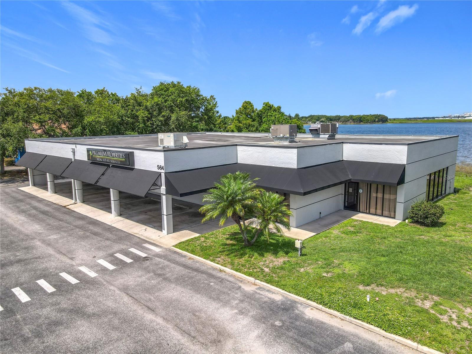Positioned in a highly convenient location, Lake Barton Office Park offers exceptional accessibility to nearly all of Orlando. Just minutes north of Orlando International Airport and ideally situated between the 408 Expressway and Highway 50 (Colonial Drive), this property is also close to Baldwin Park and within easy reach of Downtown Orlando. This professional office-zoned building sits on nearly 2 acres of waterfront property along Lake Barton and offers approximately 6,600 square feet of flexible space. With 28 parking spaces—including several covered spots—this property is ideal for a variety of professional uses. Recent Renovations include modernized reception area for a professional first impression, updated kitchen, new flooring installed throughout the building, reconfigured interior layout to include bright, open workspaces and additional private offices. Property Features: Welcoming entry lobby, three conference rooms, multiple private office spaces, three large open work areas, full kitchen and two restrooms, President’s private office with folding doors opening to a spacious wooden deck overlooking Lake Barton, three rooftop A/C units – all recently replaced and in excellent condition, interior non-load-bearing walls allow for easy reconfiguration to suit your needs, the property is currently owner-occupied and will be vacant at closing, ready for immediate occupancy or redevelopment. Additionally, a twin building next door—in need of a full renovation—is also available for purchase. While the buildings are separately titled, they share a common entry driveway and septic system. Purchase one or both to double your square footage and unlock the full potential of this prime lakefront office park.