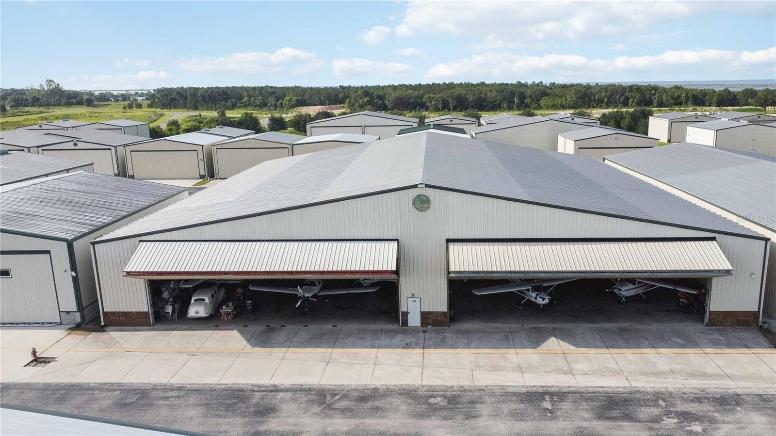 This unit is truly one of a kind. It is the largest airplane hangar at the Orlando - Apopka Airport. One of the few airports in the country where you own the land under the hangar. This unit is comprised of four parcels put together as one larger hangar. Four door access (Each door is 60 ft wide by 18.5 ft tall. gives you plenty of possibilities. Total building 154x150 Ceiling center height is 32 ft and end height is 21 ft. Private bathroom in the unit. Hangar is partially rented. Some long term leases and some short. All tenants would like to stay and all leases have a buyout clause if necessary. Contact agent for details on leases. Association pays water and sewer, owner pays electric. Association fee is stated as one unit. Property is 4 units built into 1. Sprinkler system in the unit. Bring your airplanes and imagination.