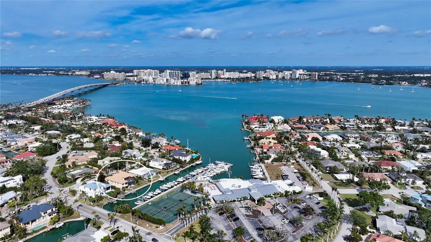 This impeccably maintained waterfront home is nestled in the exclusive Bird Key community, offering an extraordinary blend of privacy and direct, deep-water boating access. Spanning nearly 4,000 square feet, this elevated three-bedroom plus den and family room residence is designed to maximize its marina views, creating a seamless connection between indoor and outdoor living. A grand entryway welcomes you into a thoughtfully designed interior filled with natural light, soaring ceilings, multiple fireplaces, and expansive glass sliders that frame the picturesque waterfront. The open-concept living and dining areas create an effortless flow, while the gourmet kitchen is equipped with sleek countertops, custom cabinetry, island, breakfast bar, and built-in desk. A cozy breakfast nook overlooks the water, providing a serene space to start your day. The split-bedroom floor plan ensures privacy for both residents and guests. The primary suite is an oversized luxurious retreat, featuring private access to the waterfront pool deck, walk-in closets, and lovely en-suite bathroom with dual vanities, soaking tub, and walk-in shower. The guest suites are equally inviting, each offering a sunny ambiance and ample space. A highlight of this home is the dedicated office/library with walls of built-ins, perfect for working from home or enjoying a private reading space. Additional features include a custom wet bar room with temperature-controlled wine storage and abundant storage throughout. Outdoor living is a dream with a screened-in lanai, heated pool, and multiple seating areas designed for relaxation and entertaining. The property also includes a 12,000-pound boat lift with direct access to Sarasota Bay and the Gulf of Mexico, making it ideal for boating enthusiasts. Bird Key is one of Sarasota’s most coveted waterfront neighborhoods, known for its prime location and exceptional amenities. Residents enjoy proximity to the Bird Key Yacht Club, with its dining, tennis, and marina facilities. Just minutes away, St. Armands Circle offers boutique shopping, fine dining, and cultural attractions, while downtown Sarasota boasts world-class theaters, galleries, and entertainment venues. This waterfront sanctuary combines an unparalleled lifestyle with the best of coastal living.