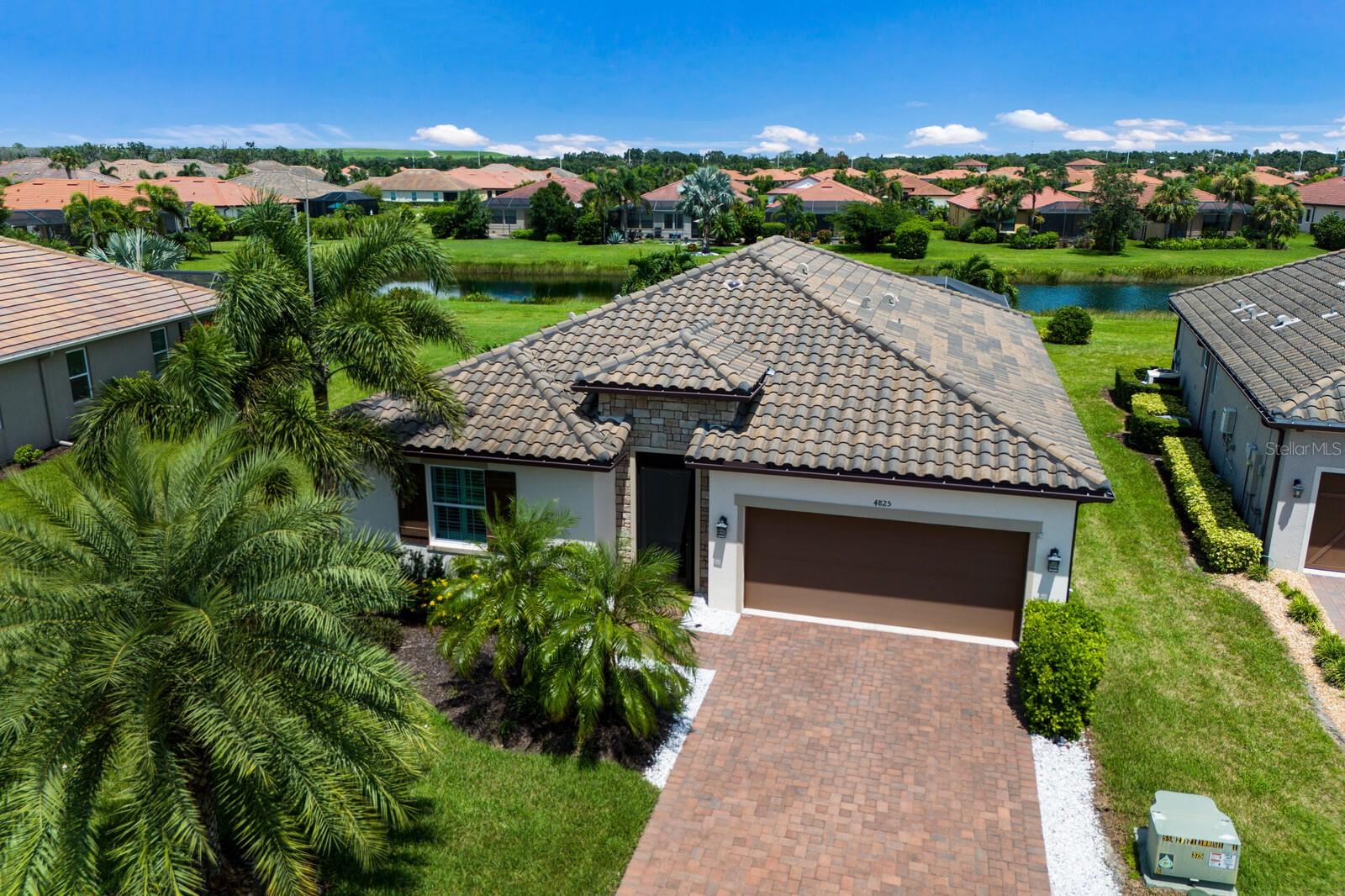 Welcome to this stunning 2019 Ashton Woods home, perfectly blending timeless elegance with modern comfort. Discover peaceful water views while enjoying your private Florida oasis with the expansive saltwater pool with spa and sun shelf surrounded by a luxurious travertine lanai. The custom outdoor kitchen boasts a gas grill, bar seating, and an extendable awning, making it the perfect spot to entertain year-round. Inside you will find a light and bright open-concept design showcasing neutral finishes throughout, including wood-look tile flooring and tray ceilings with crown molding. A welcoming entry and spacious main hallway lead you into the heart of the home—the chef’s kitchen. Complete with quartz countertops, a stylish herringbone backsplash, a gas range and nearby pantry, this kitchen is designed for both everyday living and entertaining. The large primary suite offers a peaceful retreat, featuring a spa-like ensuite bath with a seamless glass walk-in shower and a separate walk-in closet. Three additional guest bedrooms—all with walk-in closets—provide ample space, with one offering direct access to the spacious guest bath. All surrounded by lush, mature landscaping framing the large backyard and side yard, enhancing both privacy and curb appeal. Located in the desirable As a Links at Rosedale resident, you’ll enjoy an active country club lifestyle with a social membership that includes access to five Har-Tru tennis courts, a Junior-size Olympic swimming pool, a state-of-the-art wellness center, and a modern clubhouse offering a dining room, lounge, game room "19th hole" and bistro patio. With community fees covering two manned gates, dog parks, and landscaping, plus no CDD fees, you’ll relish low-maintenance living. Centrally located in Bradenton, you're just minutes from I-75, Lakewood Ranch, the UTC Mall, Gulf-coast beaches, and the Sarasota/Bradenton International Airport.