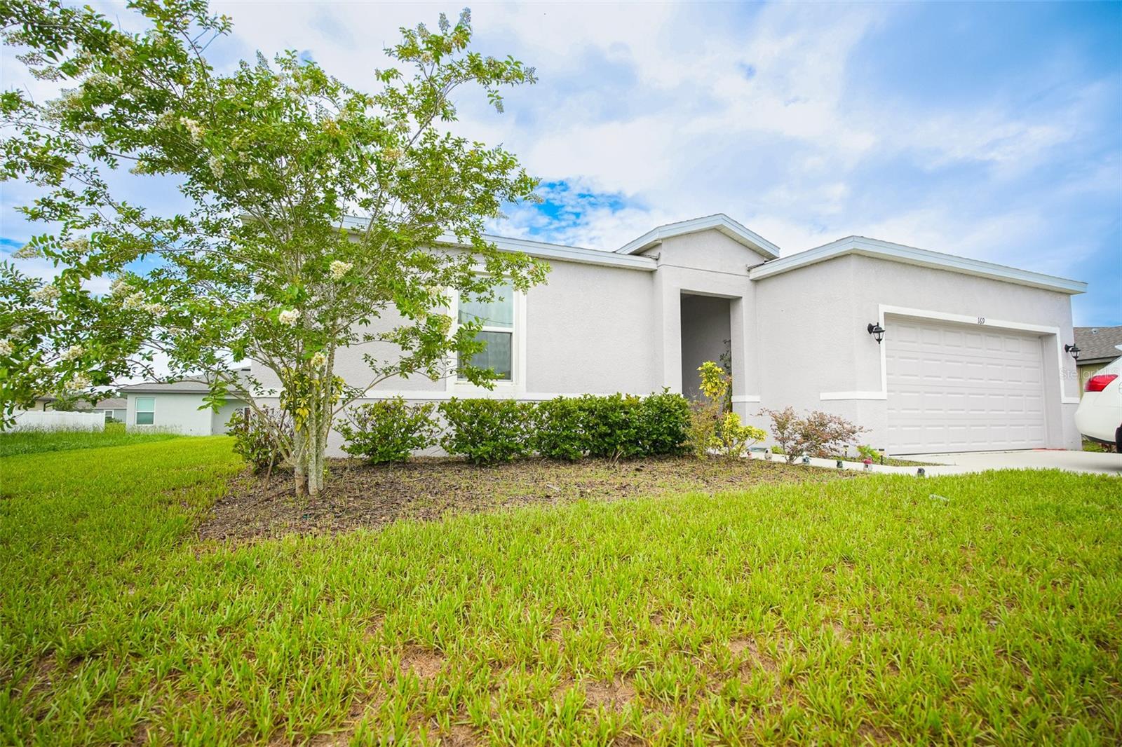 Spacious 4-bedroom house built in 2022, located in the Poinciana subdivision,. It features a two-car garage, a laundry room, and a backyard. An irrigation system with rain sensors is installed. The house has tile flooring throughout, except for the bedrooms, which are carpeted. The dining and family room are open to the kitchen. The kitchen includes appliances and a large island with a breakfast bar. The master bedroom has a spacious closet and double sinks. The bedrooms have high ceilings.