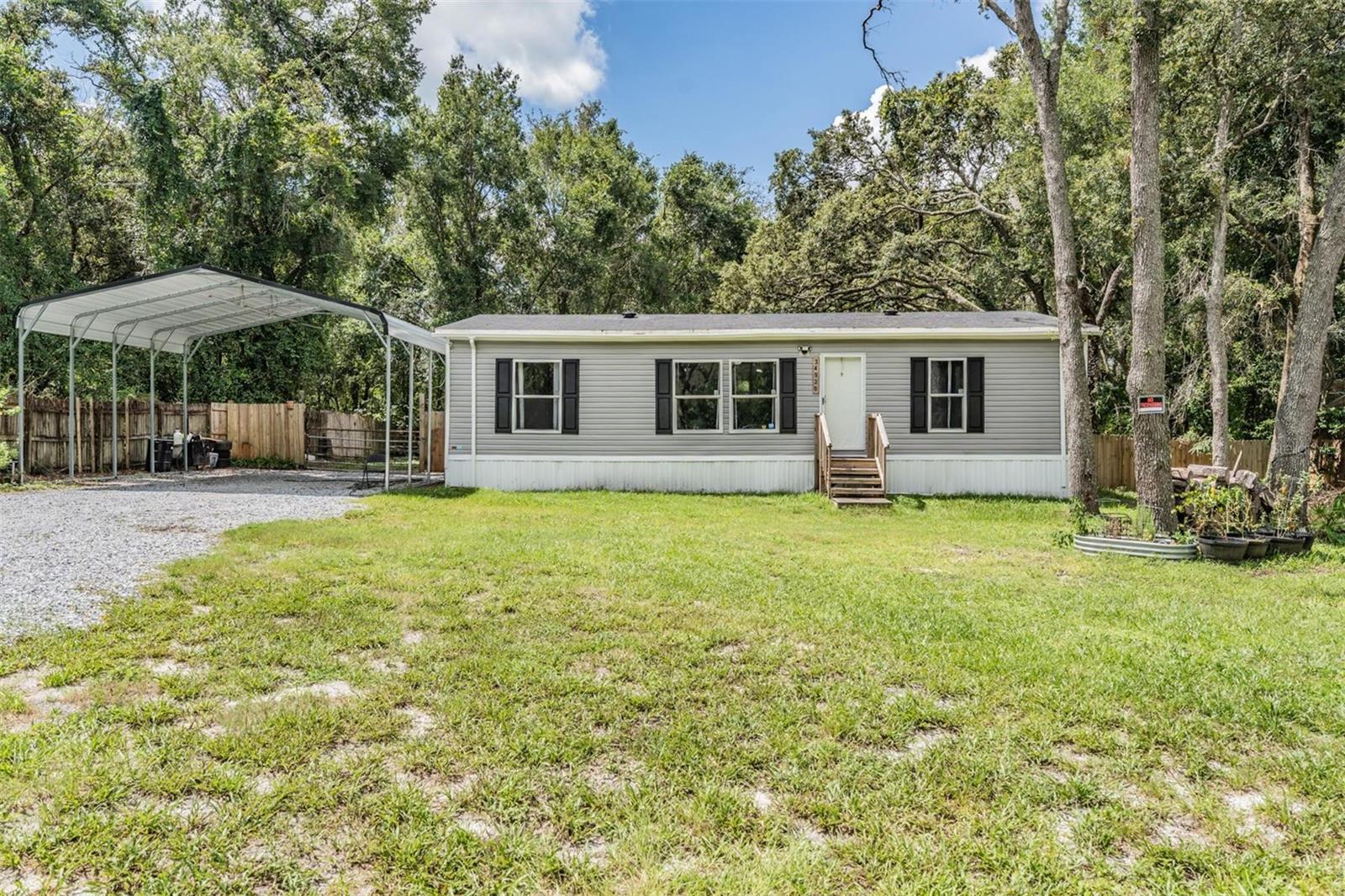 One or more photo(s) has been virtually staged. Welcome to 34930 Emily Drive in beautiful Dade City! This 2023-built manufactured home sits on nearly half an acre in the peaceful Talisman North community. Offering 3 bedrooms and 2 bathrooms, the home features an open layout with vinyl flooring in the kitchen and bathrooms and cozy carpeting in the main living areas and bedrooms. The bright, eat-in kitchen includes a cooktop stove, microwave, dishwasher and refrigerator, all overlooking the spacious living/family room—perfect for relaxing or entertaining. Brand new central air, ceiling fans throughout, and a dedicated laundry room, this home is both comfortable and convenient. The large, fenced in and gated lot along with 4-car carport provide plenty of space for outdoor living and parking. Two sheds out back for additional storage. Located in a quiet setting yet close to town amenities, this move-in ready home is a perfect blend of modern charm and everyday functionality. No HOA and No CDD fees—just easy Florida living! Schedule your private showing today!