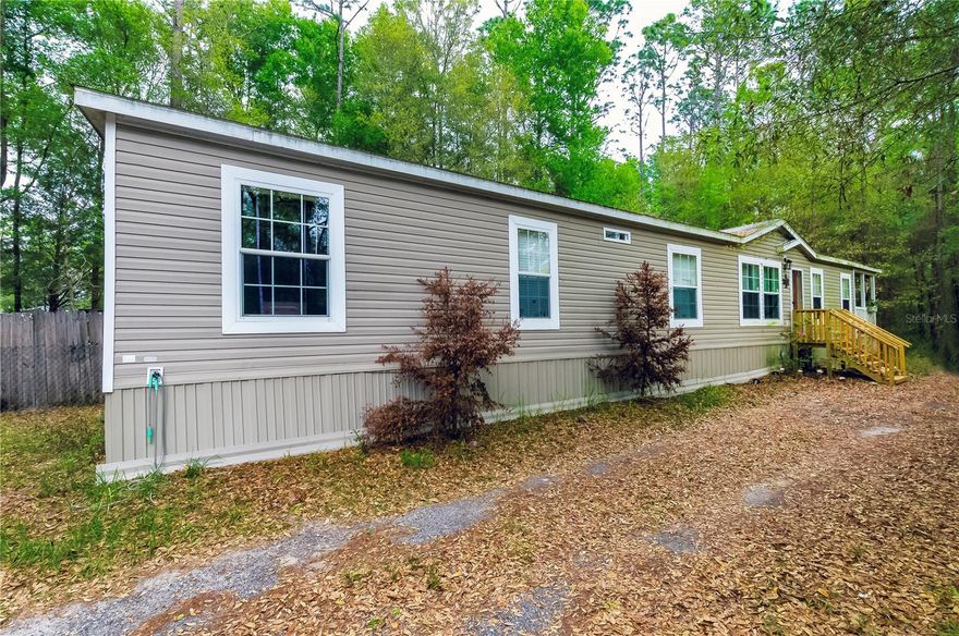 Welcome to this charming manufactured home nestled among the trees in peaceful Dunnellon, FL, offering a spacious open layout with beautiful dark hardwood-style flooring throughout. The well-appointed kitchen features a center island, tile backsplash, and black appliances, perfect for entertaining. The generous master suite boasts a luxurious soaking tub, dual vanities, a walk-in shower, and a large walk-in closet. Additional bedrooms are bright and airy, and the expansive wooded backyard provides privacy and tranquility with plenty of room to make it your own. This move-in ready gem is a fantastic opportunity in a serene natural setting