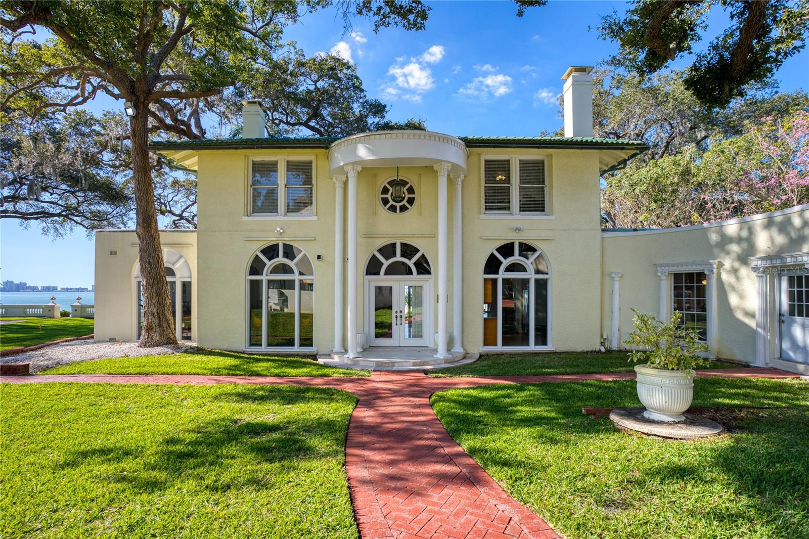 Waterfront Masterpiece in Clearwater’s Harbor Oaks. Breathtaking vistas of Clearwater Harbor and the Clearwater Beach skyline combine with manicured gardens and a coveted address to create an idyllic setting for this Greek Revival-style home in Harbor Oaks. Privately situated behind stately walls with gated access and a brick drive, the two-story home commands 1.1 acres and boasts more than 100 feet of direct waterfront along the Intracoastal Waterway. Harbor lights and city sights present a stunning backdrop for the outdoor oasis comprised of a lighted tennis court, tiered terraces, English gardens and a swimming pool. Particularly noteworthy is the exquisite observatory where spectacular Gulf sunsets are best viewed. Inside this spacious home is a sophisticated plan that redefines coastal elegance with a flair. Designed to promote comfortable family living as well as stylish entertaining, the home is appointed with an array of classic elements including crown moldings, arched doorways, custom millwork and Palladian windows. A generous display of glass doors allow natural light to fill interior spaces while also capitalizing on magnificent water views. Sized to generous proportions, the kitchen facilitates meal preparation with an abundance of storage cabinets and work space. Encompassing 6 bedrooms, 5 full and 2 half bathrooms, this waterfront masterpiece is complete with an expansive billiards room featuring a full size wetbar. The historic neighborhood of Harbor Oaks is conveniently located in the heart of Clearwater with easy access to cultural venues, recreational activities, major sporting events, world-class medical facilities and award-winning Gulf beaches.
