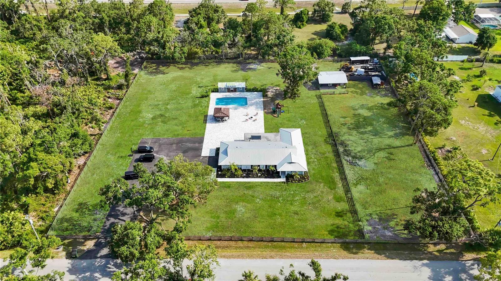 Welcome to your slice of paradise located in the heart of beautiful Sarasota, Florida. Upon arriving to this exquisite completely remodeled fully fenced and oversized asphalted driveway property a brand new electric gate welcomes you. This property is centrally located on over 2 acres offering a blend of contemporary luxury and timeless elegance, perfectly situated in the sought-after neighborhood, Desoto Acres. Step inside this meticulously designed residence and be greeted by an abundance of natural light dancing through the spacious rooms. With 4 bedrooms plus bonus room and 2 bathrooms, this home provides ample space for relaxation and entertainment. The open-concept layout seamlessly connects the living, dining, and kitchen areas, creating an ideal space for hosting gatherings or simply unwinding after a long day. The gourmet kitchen is a culinary enthusiast's dream, featuring state-of-the-art appliances, sleek countertops, and custom cabinetry. Whether you're hosting a lavish dinner party or enjoying a casual meal with loved ones, this space is sure to inspire your inner chef. Unwind in the opulent master suite, complete with a lavish ensuite bathroom, featuring a double rainfall shower head walk in shower accompanied with a center drain freestanding tub with 45- gallons of water capacity equipped with 8 Water jets and 0.75HP water pump provide a luxurious experience. Each additional bedroom boasts its own unique charm, providing comfort and privacy for family and guests alike. Step outside of the sliding glass doors to your very own oasis, soak up the Florida sunshine or lounge by the sparkling pool, or grab a cold one and sit back and relax on the newly paved outdoor arena. Whether you love to host an outdoor gathering or a relaxing dinner outside, the Paradise Grills Abaco 18' x 16' is a premium outdoor kitchen designed for those seeking a luxurious and functional backyard entertainment space. Equipped with the GS-32 Premium Hybrid Grill, this unit supports multiple cooking methods providing versatility for various culinary preferences. The kitchen includes a stainless steel refrigerator, storage doors, outlets, and an oversized bar rail footrest, all crafted from 304-grade stainless steel for durability.Integrated with an outdoor marine stereo system and speakers, the kitchen ensures an immersive audio experience. Additionally, it boasts smart app-controlled LED lighting, allowing customization of ambiance. The Avellaero stone countertops are digitally scanned from rare Italian stones and reinforced with NASA's honeycomb technology, ensuring longevity and resistance to the elements. Featuring a welded tubular aluminum frame, the structure is designed for strength and portability. The plug-n-play electrical system simplifies installation, and the oversized footrest enhances comfort during use. Have horses, pigs, or chickens? There is plenty of room for them as this property sits on over 2.5 acres with 2 barn stalls, full tack and feed room. Conveniently located just minutes from pristine beaches, world class dining, Sarasota/Bradenton airport and shopping destinations, this home offers the perfect blend of luxury and convenience. Whether you're seeking a peaceful retreat or an entertainer's paradise, this property is sure to exceed your expectations. Don't miss your opportunity to experience resort-style living in Sarasota's most coveted community.