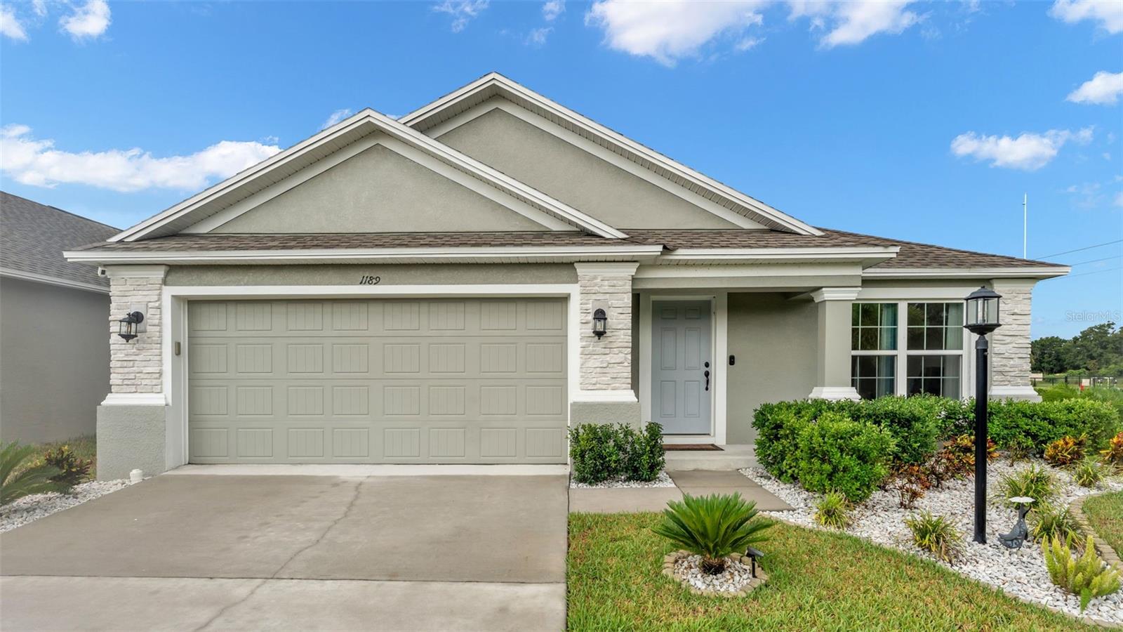 Welcome to this beautifully maintained, move-in ready home located in the highly sought-after Woodland Oaks, a gated Southern Homes development in South Lakeland. Ideally situated just off CR-540A and Carter Road, this community offers unbeatable convenience to several South Lakeland schools, shopping, dining, and more. Built in 2023 and offering 1,944 square feet of thoughtfully designed living space, this home combines comfort, functionality, and modern finishes throughout. Step inside to discover two spacious living areas—a formal great room and a cozy family room, providing ample space for both entertaining and everyday living. The home also comes equipped with upgraded ceiling fans and elegant lighting fixtures, and recently installed wood look laminate flooring throughout the entire home, including the bedrooms. The dining area overlooks the great room, creating an open, flowing layout that feels bright and welcoming. The kitchen with an island within the open living area is an absolute must see, featuring granite countertops, upgraded appliances, and sun-drenched windows throughout the common areas that flood the home with natural light. A stylish coffee bar or wine bar with built in cabinetry adds a touch of everyday luxury and flexibility to the space. Enjoy the ease of an interior laundry room with a washer and dryer included in the sale. The primary bedroom suite is privately located just off the dining area and includes a spacious ensuite bathroom with a water closet, garden tub, dual sink vanity, step-in shower, and an expansive walk-in closet. Down the hallway, you'll find three additional bedrooms, all similar in size, that share a well-appointed guest bathroom. Step outside through sliding glass doors to a large, private corner lot, fully enclosed with luxury vinyl fencing and a double gate for side yard access. A concrete patio just off the back offers the perfect space for outdoor relaxing, grilling, or entertaining guests. A home security system comes already installed with this home. The home's curb appeal shines with stone accents and a welcoming covered front entryway. But the lifestyle doesn’t stop at your front door—Woodland Oaks comes packed with resort-style amenities, including a community pool, a covered lounge area with restrooms, dog park, and tennis, pickleball and basketball courts—all within this peaceful, gated community. Don’t miss this opportunity to own a like-new, move-in ready home in one of South Lakeland’s most desirable neighborhoods. Schedule your private tour today!