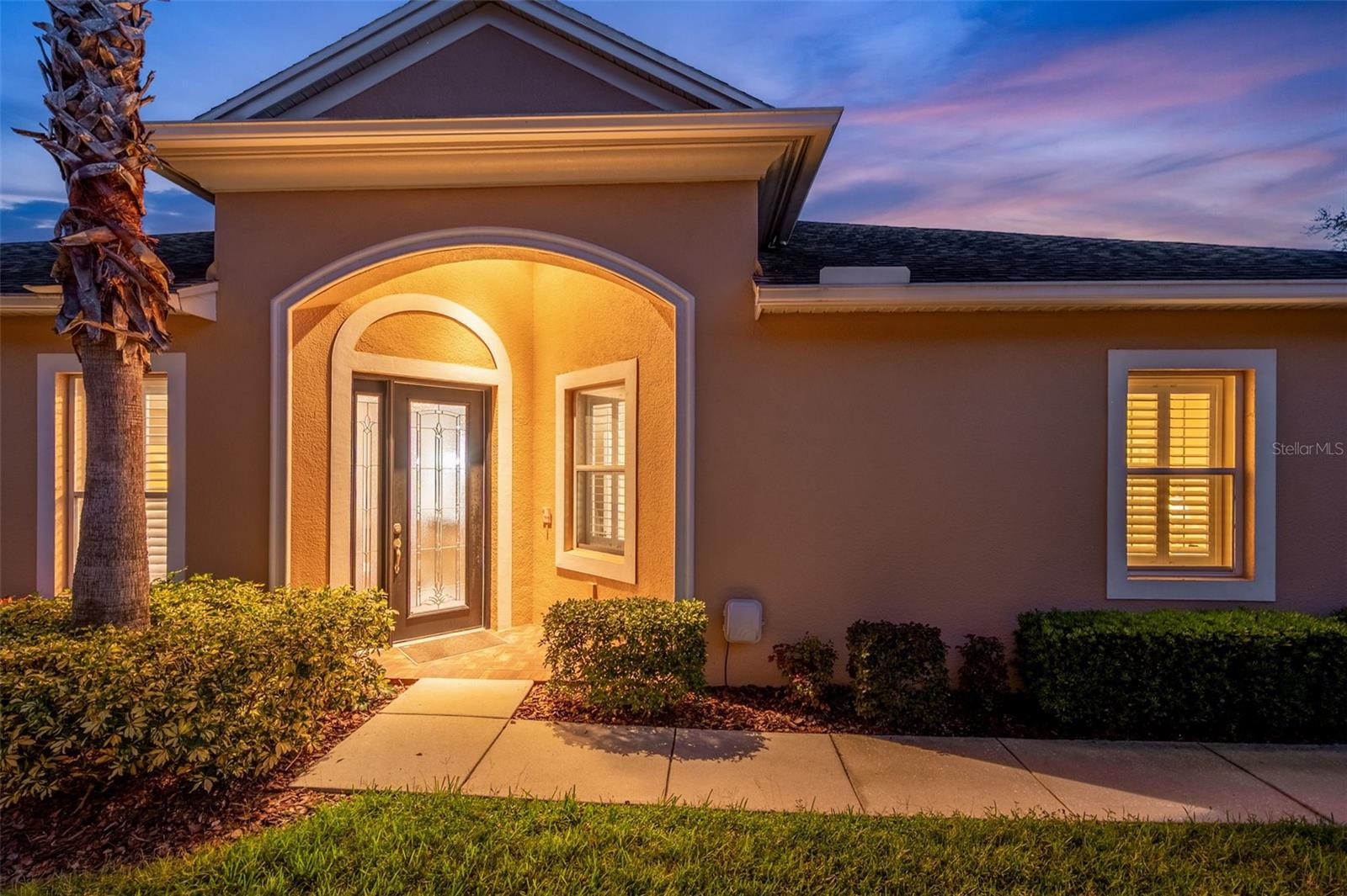GATED ENTRANCE. SERENE WATER VIEW. MAINTENANCE FREE LIVING. This beautifully maintained villa is perfectly situated on a serene pond view lot within a sought-after gated community known as Devonwood. Residents enjoy a sparkling community pool and a covered pavilion nestled in a lush green setting, perfect for picnics and gatherings. 2 Bedrooms, Den and 2-car garage. You will find features throughout that make a house feel like a “home” from the warmth of the real wood floors to the elegance of Plantation shutters to chair railing, picture-frame wainscoting, and tray ceilings throughout. Primary suite includes a serene water view, tray ceiling, double walk-in closets, en-suite bathroom with dual vanities, granite counters, glass-enclosed shower, and private water closet. Kitchen has granite countertops with breakfast bar, staggered cabinetry with tile backsplash, built-in bench with granite bistro table, stainless steel appliances, single basin sink complete with built-in soap dispenser and a detachable faucet, natural gas range, dishwasher, microwave (vented to the outside) and French door refrigerator. Den (optional office or 3rd bedroom) includes double doors and a built-in Murphy bed. Items Worthy of Mention: Tankless Gas Water Heater (2023), HVAC System (2023), Water Softener (2022), Exterior Paint (2022), Custom Glass Front Door, Whole Home Water Softener, Gutters & Downspouts, Laundry Room with Utility Sink, Cabinets, and Washer/Dryer, Interior Paint (2025) & Screened Lanai. The HOA covers roof replacement, exterior painting, lawn care, cable, internet, pool, common areas, and gated entry so you can relax and enjoy more of what you love. Perhaps some golfing? Only minutes to Plantation Palms Golf Club (approx. 3 miles) & The Groves Golf and Country Club (approx. 4 miles). Or maybe shopping? Village Lakes Shopping Center, the Shoppes at Sunlake Centre and the Tampa Premium Outlets are just a hop, skip & jump. No shortage of restaurants, shops & amenities. Buy a Little Piece of Florida Now. Survey on File. Non-Flood Insurance Required Area.