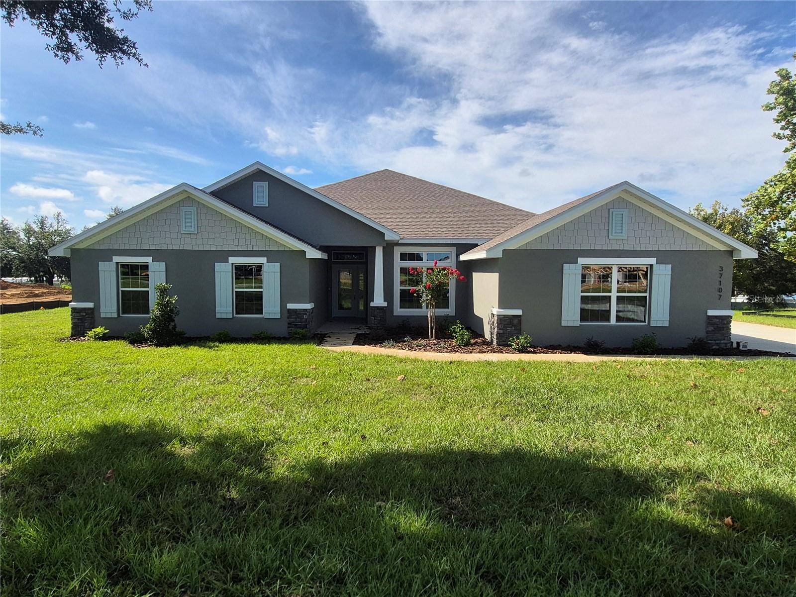 Welcome to Hill Country Estates—Dade City’s hidden gem with NO CDD fees and all the charm of brand-new construction! 4-bed, 3-bath home with a 3-car side-entry garage on a huge corner lot in a great neighborhood! Wood-look tile flows everywhere except the bedrooms, granite countertops throughout, and a massive kitchen with one island, wood shaker cabinets, and stainless steel appliances. The covered patio is 21'x10', and the owner’s suite is HUGE with a tray ceiling, crown molding, two walk-in closets, a garden tub, a separate tile shower, and a private water closet. The exterior has stone accents, and the garage doors have top-row windows for natural light. All three bathrooms echo the home’s upscale feel with matching granite counters and soft-close cabinetry. The primary suite is a true retreat, highlighted by a tray ceiling with crown molding and a stunning tiled shower with a glass enclosure. Additional upgrades include 5¼” baseboards, a 50-gallon water heater, double-pane low-E windows, and the peace of mind that comes with no flood zone concerns. Why wait to build? Your brand-new home in Hill Country Estates is ready now—beautifully finished, energy efficient, and move-in ready.