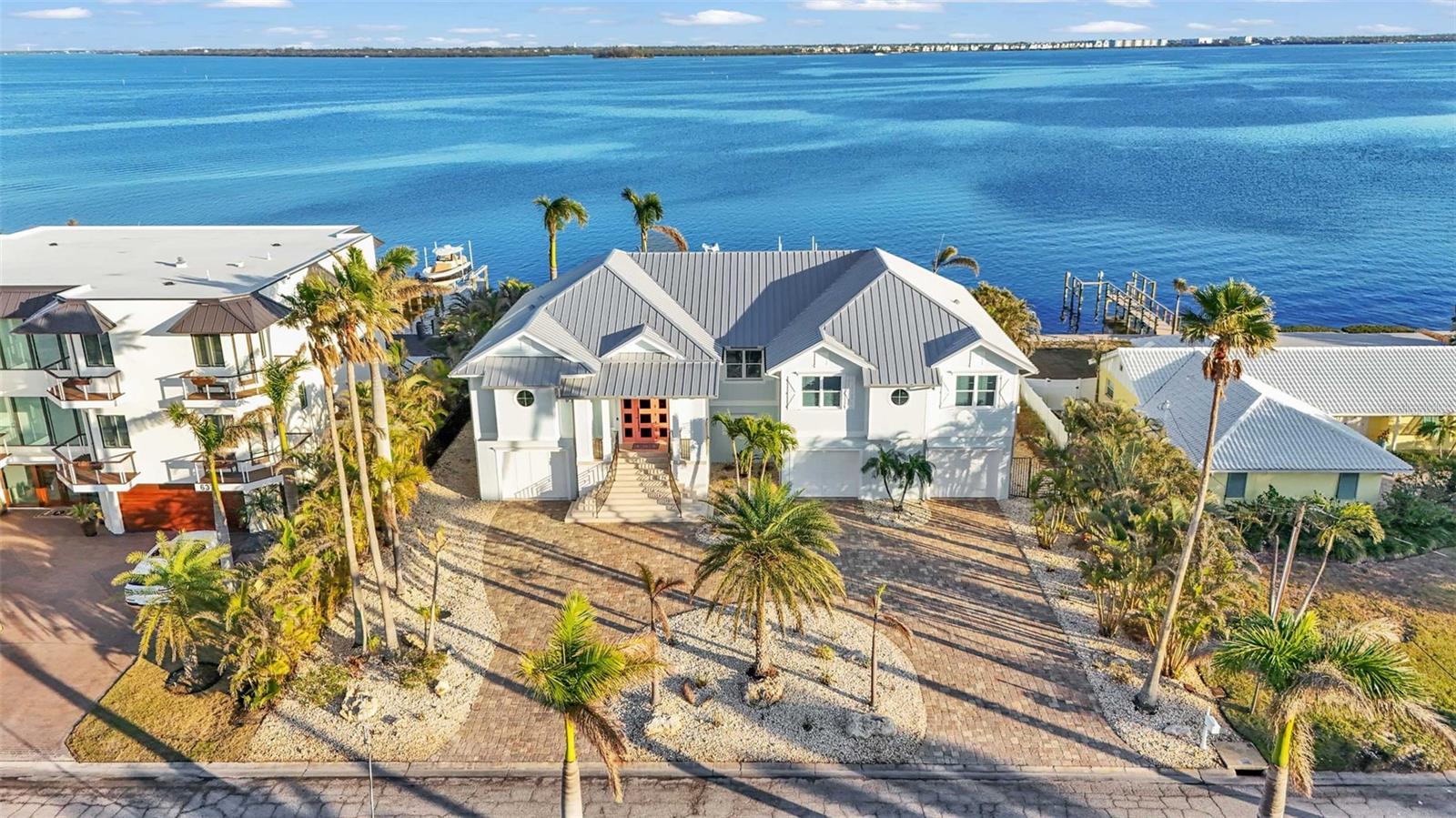 Truly A World of Its Own - Delightful Bay Front Living with sweeping views of the crystal clear waters of Anna Maria Sound and Tampa Bay. This Elevated - One level, Custom built coastal residence is a tribute to aesthetic design, location and impeccable construction, finishes and taste. Calm coastal colors and Shell stone Travertine flooring flow throughout the soaring living space featuring tongue and groove ceilings with solid wood beams, custom cabinetry with 100 year old pine accents, extensive millwork, custom handcrafted TV cabinetry, control 4 AV system, upgraded custom lighting and fans, an elevator, 8 foot solid core interior doors, a sound system, Plantation shutters and custom motorized window treatments and central vacuum. The kitchen offers Thermador commercial appliances, a built-in pantry, and double laminated edge granite counters. Bay views greet you from all angles and sliding doors lead to an elegant 63 foot balcony with outdoor kitchen and Trex stairs descending to the pool area. 3 of the 4 bedrooms are ensuite. Ipe wood flooring flows throughout the bedrooms while travertine graces the bathroom floors. Each of the bedrooms includes custom closet systems and Each of the 4 bathrooms includes Moen body wash and shower systems. The exterior construction is top notch with a commercial grade 24 gauge standing seam metal roof, PGT impact windows and doors, second floor block construction with formed and poured concrete porches, Cantera door and icynene attic insulation. The large garage space includes insulated garage doors and epoxy flooring. This waterfront masterpiece opens to a charming Bayside freeform pool/spa, large travertine pool deck with plentiful seating/dining, and covered cabana. For the boating enthusiast, this property is perfect with a Trex dock including water and electric and 28,000 and 10,000 boat lifts. This absolutely lovely home is decorator's masterpiece and a feast for the eyes. Offered furnished less personal exceptions, this residence beckons those seeking a very special house and lifestyle.