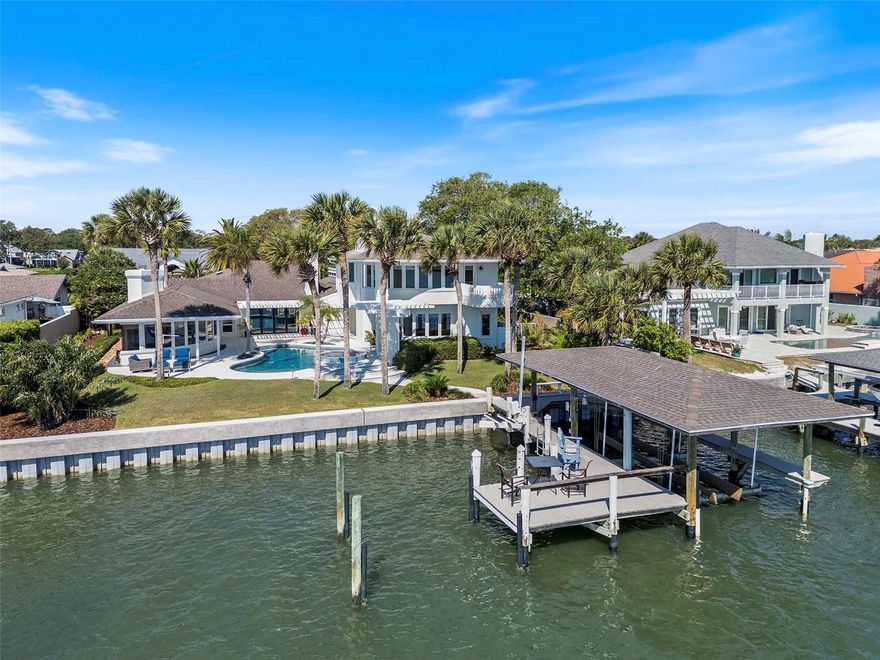 Welcome to Yacht Club Island. It would be easy to over-use superlatives in describing 1215 Commodore Dr. From the moment you enter this Custom, Intracoastal Front Residence you are captivated by the Views, the Open Spaces, the Architecture and the Light. Sunlight and Moonlight sparkle off the river and reflect off the pool. Downstairs, the spacious, open floor plan includes a Spacious, Light-Filled Living Room with natural gas fireplace and direct access to the pool area and water front lawn. Adjacent to the living room is both the Dining area and the large, Chef's Kitchen. The Kitchen boasts an 8-burner Viking natural gas range with two ovens and stainless exhaust hood, a stainless Sub Zero Refrigerator, Stainless KitchenAide Dishwasher, Viking buit-in Microwave, Double Deep Basin Sink (with a view to the courtyard), Quartz Counter Tops and Custom Tile Backsplash. The Kitchen opens to both the living room and dining room for optimal entertaining options. Adjacent to the Kitchen is a private office that opens to the shaded brick courtyard. Also adjacent to the Kitchen is the Drop Zone/Mud Room with a Sub Zero Wine Refrigerator, custom storage cabinets and direct access to the attached two car garage. From the Kitchen you also have direct access to the large Dining Area with French Doors to the intimate courtyard. Nearby is the voluminous Florida Room with stunning Eastern views of the Intracoastal and well as the pool and spa area. The Florida Room also features built-in shelves and a large natural gas fireplace. On the North side of the Living Room you'll find three bedrooms and two full bathrooms. Bedroom #2 features a 6x12 loft for extra play or sleeping space for the kids and grandchildren. Bedroom #2 also has direct access to an en-suite bathroom with tub/shower. Guests, and bedroom #3, can also access that bathroom from the hallway. Across the hall from Bedroom #4 is a large 3rd full bathroom with two sinks, a huge walk-in shower with multiple shower heads, and a private water closet. Also downstairs is a fabulous Library/Office with stunning Intracoastal views and a natural gas fireplace. This space could easily be transformed into a ground floor Primary Suite if that better suits your vision. Adjacent to the Library is a large laundry room w/ plenty of storage, a built-in desk and even a window looking out to the River. If a ground floor Primary is your goal, this space could be a large walk-in closet and laundry room.  Upstairs is where you will find the Private Owner's Retreat! This Primary Suite features yet another (the 4th of four) natural gas fireplace, sweeping water views to the East, North and South, a large (9'6"x11'7") custom walk-in closet  and a luxurious en-suite bathroom featuring a large, custom walk-in shower with its own window overlooking the pool and river. Outside, be ready to get lost in the resort-like setting. The custom pool & spa (w/ salt filtration system) offer the space to lounge & entertain family and guests. Beyond the pool area is the dock w/ covered 20,000 lb. lift. This lift has accommodated a 35' boat without sacrificing coverage. The adjacent 18'x10' deck area over the water is perfect for relaxing in afternoon breezes, watching a sunrise, launching kayaks or greeting visitors arriving by water. There is even a jet-ski lift. A Whole-House Backup Natural Gas Generator provides peace of mind. All measurements are approximate, and Buyer responsible to verify all dimensions.