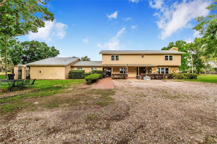 Your dream retreat in Central Florida awaits you on 3+ acres! This property features a 4BR/3BA main house and an attached 1BR/1BA in-law suite, perfect for in-laws or guests. Inside the main house, a foyer opens to a spacious living/dining area w/ a fireplace and a kitchen w/ ample cabinetry & counter space. A versatile bonus room is ideal as an office or game room, and an oversized laundry provides extra storage. Upstairs, the primary suite has a renovated bath w/ walk-in shower, and the other two bedrooms share an updated bath w/ walk-in shower. The in-law suite has a private entrance, 1BR/1BA with its own laundry, a full kitchen, and living room. Outside, a fully fenced and landscaped yard creates a private oasis, and a newer metal roof provides peace of mind. There’s also a huge 108x26 ft workshop w/ power & water, and each building has its own power meter. All this privacy, yet you’re minutes from highways & theme parks. This hard-to-find property won’t last long—don’t miss out!