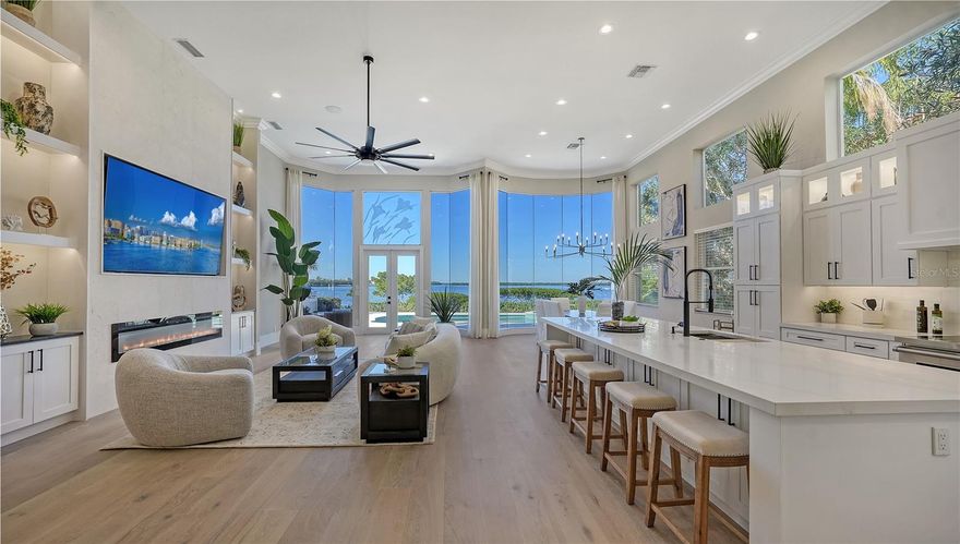 Nestled in the prestigious Queens Harbour community, this beautifully renovated direct bayfront residence offers the epitome of luxury living. Recently updated in 2023/2024, this fully furnished three-bedroom plus den home showcases an exquisite open layout that highlights the breathtaking bay views from every angle. With its contemporary gourmet kitchen, modernized bathrooms, and sleek hardwood flooring, this residence is a masterpiece of design, offering both comfort and chic style. The spacious open layout spans nearly 3,100 square feet and boasts walls of glass, equipped with storm shutters, framing the serene Buttonwood Bay views while also providing easy access to the sun-drenched pool deck and deep-water dockage. The star of the show as soon as you enter the double doors is undoubtedly the remarkable bay waters visible from the moment you step inside. The living room features cathedral ceilings, custom built-ins, and electric fireplace, creating a warm and inviting atmosphere. Just steps away, the dining room is surrounded by floor-to-ceiling bay windows, immersing you in the captivating scenery. The chef's kitchen is a culinary dream, with Quartz countertops, an extended island with storage on both sides, and room for at least five to dine. Custom shaker-style cabinetry with black fixtures, under-cabinet lighting, and glass cutouts provide a striking contrast, adding to the kitchen's appeal. The primary suite, nestled on the northeast side of the home, offers a private retreat with brand-new his-and-hers closets, a spa-inspired en-suite bathroom, and a bayfront sitting area. Glass French doors open to the pool deck, allowing you to seamlessly transition between indoor and outdoor living spaces. On the west side of the residence, you'll find a cozy den/study (recently added) and two generous guest suites. These well-appointed rooms ensure your guests feel right at home. Outside, the expansive pool deck is bathed in sunlight and features a built-in grilling station, a sparkling swimming pool, and a heated spa. Beyond the pool area, a boardwalk leads to the deep-water dock, perfect for boating enthusiasts. Queens Harbour is known for its serene privacy, offering residents access to a community spa and an Olympic-sized heated swimming pool. The neighborhood's peaceful setting is complemented by its proximity to the Bay Isles Beach Club, where residents have deeded access to the private beach Club just a short bike ride away. This central location provides easy access to all the best that Longboat Key has to offer, from the Longboat Key Club's prestigious Islandside and Harbourside facilities to the nearby Publix shopping plaza, established eateries, St. Armands Circle, and downtown Sarasota.