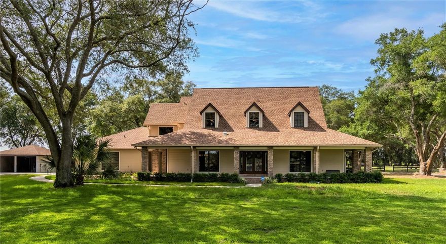 Under contract-accepting backup offers. Stunningly positioned within the equestrian community of Starting Point Horse Complex, this beautifully designed horse farm overlooks 21 acres of pristine Central Florida countryside. Nestled amongst mature oaks and accented by tasteful landscaping and a large country-style covered porch, this custom home has a private setting and an attractive appearance. Offering a total of 4-bedrooms, 3-full and 2-half baths, the home has a variety of upgrades throughout that exudes a luxurious like-new feel. The interiors of the home feature ample natural light, tall ceilings, and stunning views throughout. A cozy fireplace serves as the focal point for the family room, which also features stunning cathedral ceilings and stunning french doors out to the pool area beyond. Those who enjoy cooking will love the tastefully equipped kitchen, which comes with stainless steel appliances including a convection Wolf Range, Sub-Zero refrigerator and freezer, a built-in ice maker, custom wood cabinetry, granite countertops, center island, breakfast bar, and an adjacent breakfast nook. The formal dining room is a wonderful entertaining space with stunning custom built-ins that include a built-in wine fridge. All bedrooms are well-appointed, though the first-floor primary suite is a true stand-out that offers an extra-large layout, bay-style windows, direct pool access, and a private en-suite with custom wood cabinets, dual vanities, walk-in shower, and dual walk-in closets with California closet systems. A large second-floor landing overlooks the family room and entryway, equipped for all your media needs. The remaining bedrooms are also located on the second floor, all of which include custom closet systems. To the back of the home is a large screen-enclosed pool area that boasts a stunning covered area with tongue-and-groove ceilings, a built-in summer kitchen, and a sparkling heated chlorine-free pool. Additional upgrades include new AC units, a gas pool heater, solar panels, and a new well. A new whole-home generator keeps the power running even during an outage, and an additional generator is at the barn for added protection. For horses, the farm features a 10-stall center aisle barn with feed and tack room, fly spray system, half-bath, washers and dryers, and wash rack with hot water. There are paddocks conveniently close to the barn with several larger turn-outs on the property. A new 120 x 300’ GGT all weather arena with irrigation has also recently been put in place. For convenience, 3 full RV hook-ups are located on property. On the west side of the property is a large metal building for equipment and storage. A third of this building is currently in the process of being converted into a flex space. Conversion is planned to continue until the property is sold, and all unused materials are included for the buyer to finish their way. Starting Point is a wonderful option for equestrians with bridle paths that run throughout the community and both HITS and World Equestrian Center just a short drive away. A furnishing package is available.