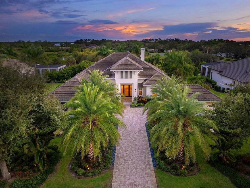 Located in the prestigious Lake Club of Lakewood Ranch, this 2020-built West Indies–style estate offers 3 beds and 3 baths on 0.42-acre lot. A paver driveway, stone-lined landscaping, and coach lights frame the exterior, while impact-rated windows and doors, a Kohler whole-house generator, surge-protected electric panels, a 3-zone HVAC system, and a tankless water heater provide peace of mind. The home offers three garage spaces, an attached two-car garage, and a separate one-car bay, each fitted with paneled doors. The entry sets the tone with a custom rain-glass front door, a transom window, and a feature wall of framed wallpaper panels. Inside, crown molding, engineered hardwood floors in the living areas, and a seamless flow between rooms. The great room features a tray ceiling, a tiled gas fireplace with custom shelving, surround sound, and a zero-corner wall of sliding glass doors that open fully to the lanai. The office, accented with iron and glass walls and a barn door, is finished with designer wallpaper and a picture window. The kitchen is anchored by an oversized island with a porcelain countertop, pendant lighting, and a custom-trimmed base, complemented by dark perimeter cabinetry with a waterfall-edge quartz counter, glass-faced uppers, upgraded gold hardware, and pull-out shelving throughout. GE Monogram stainless-steel appliances include a six-burner gas stove, oven, microwave, vent hood, refrigerator, and dishwasher. A dry bar with a wine cooler, a reverse osmosis system supplying both the sink and freezer ice maker, and a walk-in pantry with a coffee bar add convenience. The primary suite is a retreat with a beamed shiplap tray ceiling, wallpaper accents, and pocketing sliders to the lanai. Dual custom closets are heavily upgraded and include custom lighted cabinetry, auto-motion lighting, thoughtfully organized built-ins, and plug-ins inside drawers. The spa-like bath features dual vanities, porcelain and ceramic finishes, an oversized glass shower, and a Toto washlet in a private water closet. Two guest suites each include walk-in closets with auto-on lighting and stylish en-suite baths, one with wallpaper, a trimmed mirror, and a glass shower, the other with access to the shared pool bath accented by custom tile, decorative finishes, and linen storage. A bonus room with surround sound, designer wallpaper, and expansive windows adds versatility. The lanai offers southern exposure and preserve views, with a heated saltwater pool and spa finished in iridescent tile. Custom Pecky Pine ceilings, surround sound, and panoramic screens frame the space. The outdoor kitchen features a waterfall-edge quartz counter, Alfresco grill, vent hood, tiled cabinetry, and blue backsplash, paired with Silver River Travertine flooring and generous seating areas for gatherings. The tiled laundry room includes cabinetry, folding space, and a GE washer and dryer, while the mudroom landing near the garage adds shiplap and two storage closets. The two-car garage is complete with built-in cabinets, a workspace, utility racks, and an EV charger. Residents of The Lake Club enjoy resort-style amenities, including pools, a renovated clubhouse with dining and bar, fitness center, spa, tennis, pickleball, playground, dog park, and the services of a concierge and activities director. The community is also minutes from UTC, LWR Main Street, Waterside Place, and world-famous beaches. Furniture is available in a separate package.