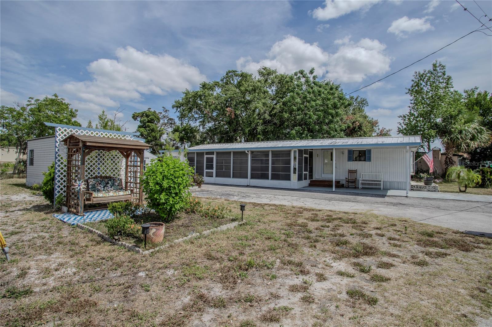Price reduced!! Seller recently replaced plumbing and electrical service at the pole. PLUS the tie-downs have been upgraded to code!!
Come to beautiful Lake County Florida and enjoy the relaxing lifestyle of this 55+ community. This two bedroom, two bath fully furnished home on a double lot (one lot can be split out and can be sold and used for another residence) has a spacious well-equipped kitchen that opens to the living room. The primary bathroom has been recently renovated with a walk-in shower, new vanity and luxury vinyl plank flooring. The kitchen has an area for eating, a breakfast bar, and an island that gives additional space for baking or entertaining. Relax in the oversized Florida room, or tinker in your 12 x 24 shop. Property also includes a shed for your lawn equipment. All furnishings, decor and supplies are included. Lawn equipment in the small shed is also included. The shop is still being cleared out. Property is under Video Surveillance 24/7 inside and out, please do not tour property without an appointment with your Realtor.