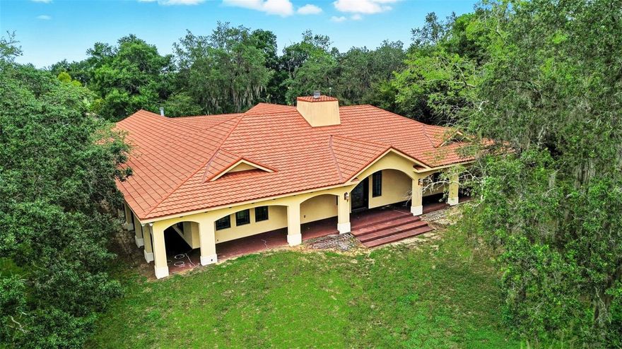 Welcome to this one-of-a-kind GOLF FRONT equestrian estate home on 5 high and dry private acres. This mediterranean property features over 6,500 of living SQFT with 4 bedrooms, 3 full bathrooms, 2 half bathrooms, extensive natural light throughout, 2 fireplaces, 2 laundry areas, a theater ready room, ample entertaining space all thoughtfully positioned between a North and South wing. The primary suite is situated in the South wing and has its own private fireplace with extensive views of the 14th fairway of Champion’s Gate award winning National Golf Course, a massive walk-in closet and custom travertine fitted bathroom with jetted tub, separate shower and dual vanities. Extra rooms in the South wing include a massive laundry room/utility room, flex room off the kitchen (play room, office, storage) and a half bathroom. Additionally in the South wing is massive 14+ seat dining room and the top-of-the-line custom kitchen with all wood Bertch cabinets, extensive level 5 granite countertops, a Miele Dishwasher, a Fisher & Paykel 2 drawer dishwasher, GE Monogram under counter 2 drawer beverage refrigerator, Sub-Zero built-in refrigerator, double Miele ovens, a Miele warming drawer and a Miele 5 burner cooktop. The North wing features 3 bedrooms (or 2 bedrooms and an office), 2 bathrooms, 1 half bathroom, a theater ready room, a laundry closet, and two additional living rooms. The center of the home features a massive great room with cathedral ceilings, a double-sided fireplace and the grand entryway with a custom iron front door, travertine flooring and ample storage. The home is surrounded by over 2,700 SQFT of covered outdoor space and is centered on a large 1,100+ SQFT courtyard. Other features include 2 water heaters, double pane windows and doors, custom millwork around each window, solid core doors, rounded drywall edges, architectural niches, barrel tile-look metal roof, spray foam insulation, 2 a/c’s, a private well and all of this on a private 5 acre lot. Within minutes to Disney World, Seaworld, Universal, award winning shopping and restaurants and short access to multiple golf courses and the interstate. The property has the feeling of being rural and still within minutes of all that Central Florida has to offer. Don’t miss the immersive virtual tour!