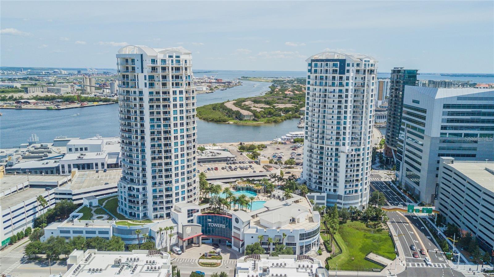 Welcome to Unit 2703 — a very rare opportunity to own one of the largest high-rise condos in the heart of Downtown Tampa. With 2,786 square feet of interior space and 1,043 square feet of private outdoor living split between two balconies, this residence offers an exceptional blend of size, views, and layout in one of the city’s most vibrant locations. Perched on the 27th floor, enjoy unobstructed panoramic views of Sparkman Wharf, the Florida Aquarium, cruise ships coming and going, Beer Can Island, and the glittering downtown skyline. You’ll even have front-row seats to Tampa’s legendary 4th of July fireworks show — all from your private balconies. Inside, a spacious and open floorplan features floor-to-ceiling windows, high ceilings, and original quality finishes throughout. The kitchen, dining, and main living areas flow seamlessly to the oversized primary balcony, ideal for entertaining or taking in sunrise and sunset views. The primary suite offers private balcony access, dual walk-in closets, and a large en suite bath, while the two additional guest bedrooms are tucked away on the opposite side of the residence — each with access to their own shared balcony, creating the perfect guest retreat or flexible workspace.
This unit also comes with two large, dedicated parking spaces and a climate-controlled storage unit — a valuable convenience in downtown living. Enjoy full access to luxury amenities including 24-hour concierge service, resort-style pool and spa, modern clubhouse, and secure garage parking. Located just steps from Water Street, Amalie Arena, Sparkman Wharf, the Riverwalk, and Tampa’s best dining, shopping, and entertainment. Unit 2703 combines rare square footage, stunning views, and unbeatable walkability — offering one of the most compelling opportunities in downtown Tampa.