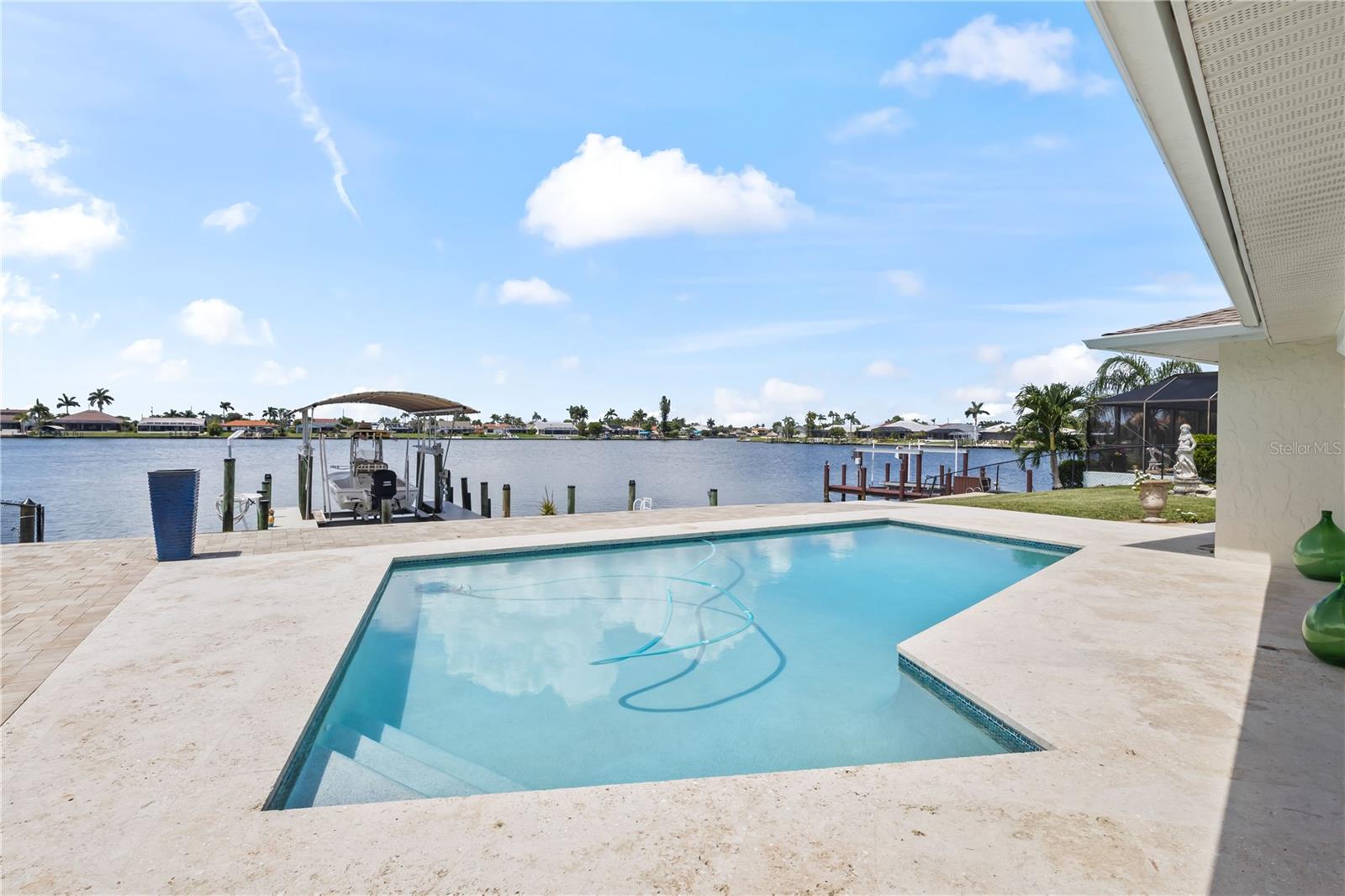 Lakefront Gulf-access pool home with premium upgrades and timeless Florida charm! Located on one of Cape Coral’s desirable 8 lakes, this beautifully remodeled property offers direct boating access to the Gulf along with a private dock featuring a 10,000-pound boat lift, upgraded 2” TanDeck decking, and a reinforced 4” concrete davit area—ideal for serious boaters. Inside, you'll find spacious bedrooms, abundant natural light, and modern finishes throughout. The indoor laundry room offers excellent functionality with ample cabinet storage and a granite countertop that’s perfect for folding. Other upgrades include a newer roof, a new pool pump, and a whole-house water softener with reverse osmosis system. The fully fenced yard adds privacy, and the pool area shines with a resurfaced deck finished in elegant Turkish Stone. Whether you're relaxing by the lake or heading out on the water, this home delivers the best of the Southwest Florida lifestyle.