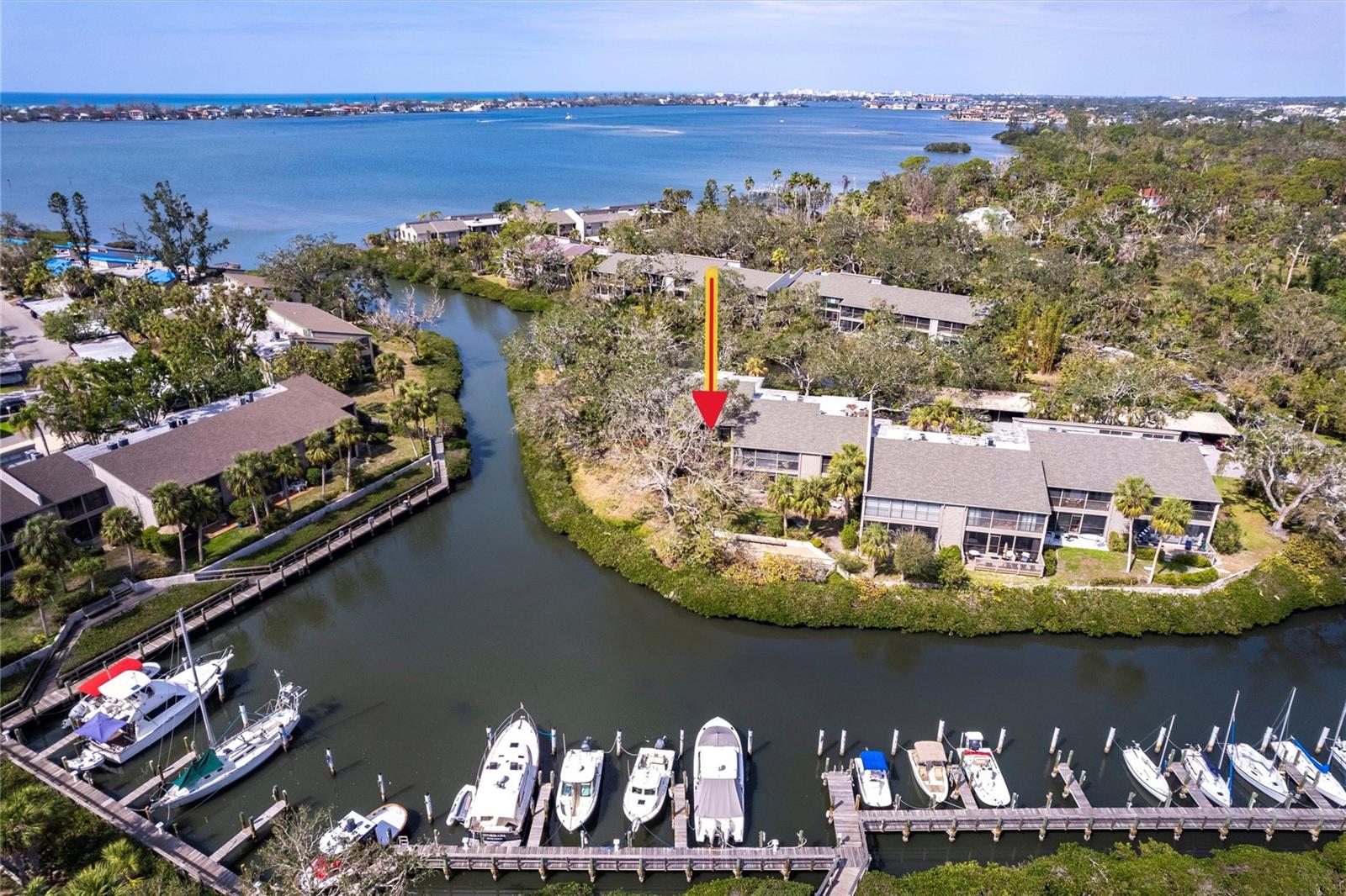 One of the premier, PREMIER units in all of Pelican Cove! Location has it here! This condo is on a cul-de-sac point with water views on three sides. Inside, the kitchen has been beautifully redone with subtle cream raised-panel cabinetry and modern pulls, laminate floors, and a handsome quartz countertop. The kitchen was opened with walls removed and has all stainless appliances. This is a split bedroom floor plan and the primary bedroom is ideal for a large family room right on the water. Two bathrooms have varying degrees of updating and both include newer Silestone vanities. There are three patios-the rear 23-foot patio is sliding glass-enclosed and overlooks the 87-slip boat harbor, the primary bedroom has another sliding glass-enclosed private terrace and also an open patio looking over the creek, boat harbor entrance canal and Little Sarasota Bay in the distance. The condo is awash in light with clerestory windows, cathedral ceilings, and end unit windows. All of the sliding glass doors are hurricane impact doors. Enjoy new ceiling fans, some newer lighting, newer receptacles, switches, electric panel, and water heater. This comes very well furnished with few exceptions. Come see this rarely available floor plan on a private peninsula surrounded by relaxing water, shade trees, and nature. PELICAN COVE FEATURES includes over 32 organized clubs including art & sculpture, active yacht club, folk music, photography & cinema clubs, social clubs, and many more. There is a for-fun “Pelican Cove University” covering several diverse subjects, woodworking studio, many card-playing clubs, water exercise and yoga, and a tennis club. There are several yearly jazz and cultural concerts and a few harborside concerts as well. Pelican Cove has a 24-hour gated and staffed entrance, 87-slip boat harbor with over 130 kayak/canoe storage racks & launch docks, fishing docks, three active clubhouses, exercise room, six heated pools, hot tub, shuffleboard, basketball, dog walk area, 5.5 miles of meandering boardwalks & nature trails, and four lighted tennis/pickleball courts all in an award-winning community with unbelievably well-manicured tropical grounds! Welcome to Pelican Cove!