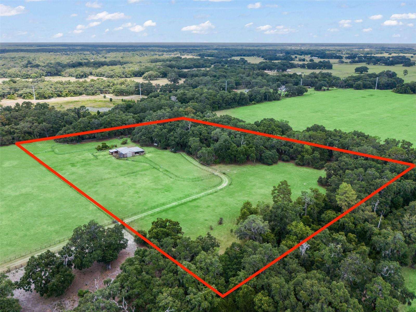 Privacy abounds at this 15 acre horse property centrally located in Bushnell at the end of a dead-end street - no roads touch this property! Enter the property though the automated gated entryway complete with zombie lock for added security. Pass several cross fenced paddocks and the drive leads to the home nestled in a mature hammock of age old oaks and a variety of stunning mature landscaping, which you will find throughout the property. The large and welcoming covered front porch is sure to be one of your new favorite places, perhaps until you find yourself rocking on the covered back porch. Inside, this special home features hardwood & tile flooring and vaulted wood ceiling with a spacious and functional open layout, perfect for entertaining. The open kitchen overlooks the living space and offers a long island with room for several barstools, soft-close cabinetry, a closet pantry and Jenn Air dual fuel range with gas cooktop and double electric ovens. The primary suite features access to the back porch and an ensuite bathroom with walk-in shower. The split bedroom layout offers two additional bedrooms on the opposite side of the home with a shared bathroom in between. There is also a laundry room leading to the front porch, doubling as a mud room. You are sure to appreciate the two thoughtfully designed, center aisle horse barns with 13 stalls measuring 11' x 14'. The "Stud Barn" has 4 reinforced stud stalls, 2 regular stalls and an attached 1,300 square foot shop/equipment storage area with industrial shelving and doors on 4 sides. The "Mare's Barn" has 7 stalls, a cedar walled tack room with tree log saddle racks and a separate lab room. You will also find inspection chutes and cross tie areas at both barns, wash rack, 1/10 mile riding arena, 7 cross fenced Pensacola Bahia pastures with water to each, 4 paddocks, private pond, greenhouse, 3 duck/chicken pens, and an incredible array of plants and wildlife. This exceptional property, comprised of two parcels (10 and 5 acres each) with separate power access, also offers an ideal layout for a multi-generational family compound or private homestead—with ample space to add guest homes, additional dwellings, or extended living quarters as desired. Centrally located just 3 miles to the soon-to-be Aldi shopping center and approx. 1 hour from Tampa, Orlando or Ocala with easy access to i75 and the FL Turnpike. This is truly a property you must experience in person to appreciate all it has to offer. Please enjoy the attached video and 3D tours!