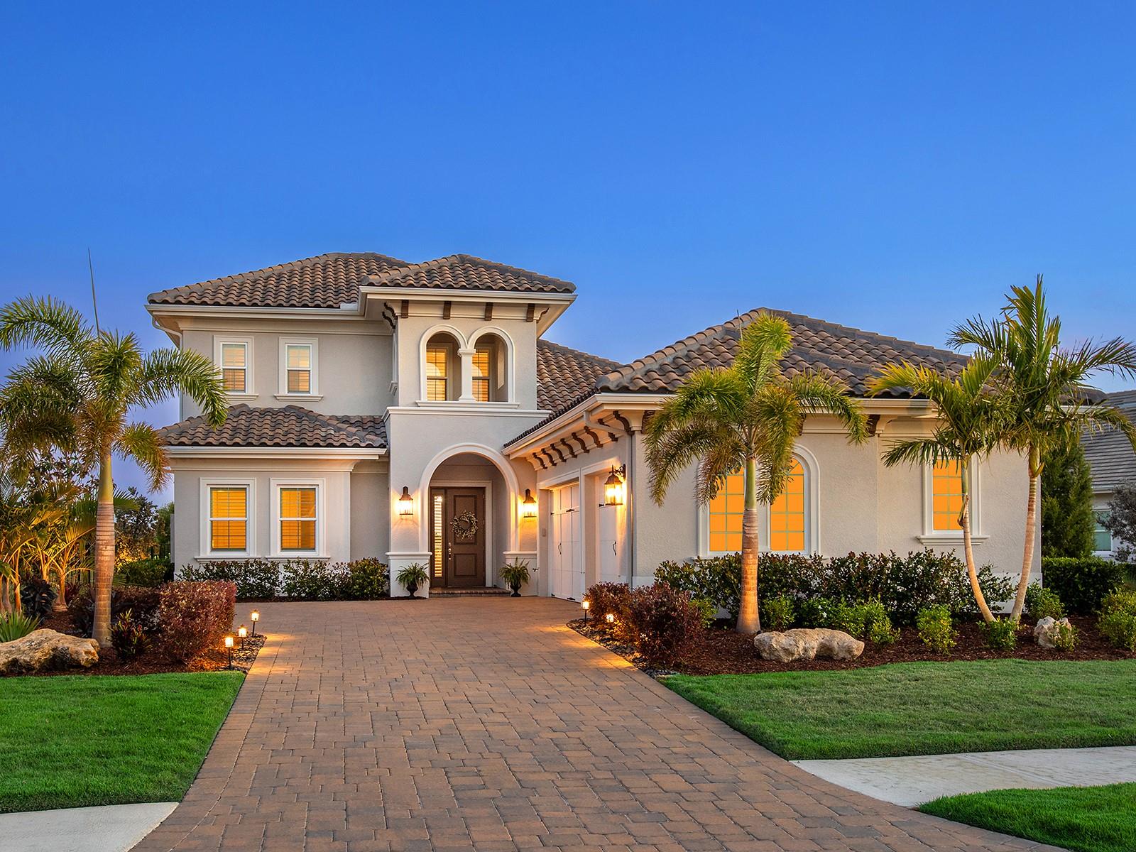 This is an exceptional residence tucked within the gates of Lakewood Ranch’s exclusive community, The Lake Club. With its elegant Eaton Grand III floor plan, this 2021-built estate offers effortless luxury. The home’s stately curb appeal sets the tone from the moment you arrive, with a side-load three-car garage, oversized paver driveway and manicured landscaping. Step through the front door into a soaring foyer adorned with accent trim, crown molding and a designer chandelier. Throughout the home, rich engineered hardwood flooring, plantation shutters, and sophisticated finishes speak to the care and detail poured into every room. The great room is an expansive space framed by a wallpaper accent wall and a striking linear fireplace with herringbone shiplap and a wood mantel. Pocketing sliders disappear to connect indoor-outdoor living. The kitchen boasts stainless steel KitchenAid appliances, including a five-burner gas cooktop with a statement hood and built-in oven and microwave/convection, granite countertops, stone backsplash and abundant cabinetry with under-cabinet lighting. A generous pantry cabinet, a lazy Susan corner cabinet, and an oversized island create ease for daily routines and entertaining. Just off the kitchen, the dining area is flooded with natural light from two large windows and elevated by a designer chandelier. Secluded in its own wing, the primary suite is a private retreat featuring an alcove entry, shiplap accent walls, a sitting area and two custom walk-in closets with thoughtful built-ins. The en-suite bath is complete with dual vanities, a soaking tub, a walk-in shower and a private water closet. Three additional bedrooms provide comfort and flexibility. One guest suite includes a private bath, while two more share a full bath in a cleverly designed pocketed guest wing. A quiet office, accessible through French doors, offers the perfect space for a home office or library. Upstairs, the loft offers versatile bonus space while an adjacent fitness room, or potential fourth bedroom, features three large windows and a spacious closet. A full bath with quartz-topped vanity and tub/shower completes the upper level. Step out to the lanai and enjoy a covered seating area centered around a custom media wall. The fully equipped summer kitchen includes a built-in Blaze grill, sink, mini refrigerator and granite countertops. The saltwater pool and spa await with blue tile accents, LED lighting, waterfall bowls with fire features and a sun shelf. A dedicated pool bath with quartz vanity and tile floors adds ease, and the included sauna invites relaxation. The lanai is getting a brand new cage in July 2025 (approx). The fenced yard, bordered by mature landscaping, creates peace of mind for pets or children. Additional features include a well-appointed laundry room with granite counters and ample cabinetry, a large storage space under the stairs and a spacious three-car garage. In The Lake Club, residents enjoy access to a wealth of amenities, including two resort-style heated pools, a recently renovated clubhouse with fine dining and bar area, a fitness center, spa, tennis courts, pickleball, a playground, dog park, and services of a full-time concierge and activities director. Additionally, residents are near The Mall at UTC, LWR Main Street, Waterside Place and dining options. Experience luxury living in this home, where every detail has been carefully considered to provide the ultimate Lakewood Ranch lifestyle.