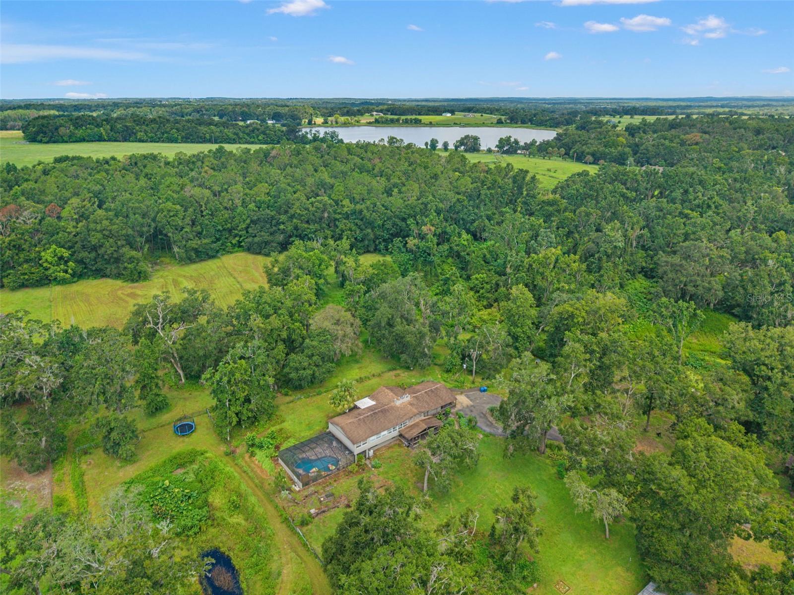 Endless opportunities at this incredible property on 10.3 ACRES! Zoned AG + additionally zoned for an Assisted Living Facility, this property features a 9 bedroom 4.5 bathroom home with a POOL, a detached guest house, 8 fully fenced pastures, and multiple barns. Bring your animals! The main home with stunning stone accents and Hardie Board siding boasts over 5,100 of heated square feet! Upstairs is a large kitchen, formal dining room, spacious living space with wood ceilings, 5 bedrooms, and 2 bathrooms. Downstairs is a second full kitchen, living room, 4 bedrooms, and 2.5 bathrooms. A beautiful stone fireplace runs through both floors in the living rooms. The half bathroom has an exterior door - perfect for when working outside. There are primary bedrooms on both floors and multiple exterior doors for easy access in and out. The downstairs primary bedroom already has plumbing in place if you wanted to add a kitchenette. This home would work well for multifamily or even to live on one floor and rent out the other one. There are a total of 5 covered porches around this home and the front porch has the most beautiful sunrises from the neighboring pasture. Main home Roof 2017. In addition, this home is ADA Accessible! The fully screened saltwater pool was resurfaced 2 years ago and is also ADA Accessible with a lift. The above ground hot tub conveys with the property as well. The larger barn is 2,464 square feet and can hold up to 8 cars and is abundant for storage on this property. The detached guest house is a 1 bedroom 1 bathroom with all plumbing and utilities currently connected. The guest house needs cosmetic renovation but all the bones are ready for you! There is a 3rd covered barn with multiple stalls sitting on a slab, and a 4th small covered structure in one of the pastures. Additional features of this property include an electric gate, a paved driveway, elderberry, banana, and orange trees, a small pond, a feeding trough, and beautiful flowers and wildlife throughout. There are so many personal and business opportunities here. You can live here and enjoy everything this home has to offer and simultaneously you can run an agricultural business out of this home and potentially qualify for a massive tax exemption. This is truly a rare and unique opportunity in arguably one of the best areas in Brooksville! BONUS TO BUYERS - Seller is offering the 5 Alpaca to convey with this sale! Located less than an hour from Tampa International Airport and Busch Gardens, 1.5 hours to Disney World, and within 15 minutes to multiple shops, restaurants, and hospitals.