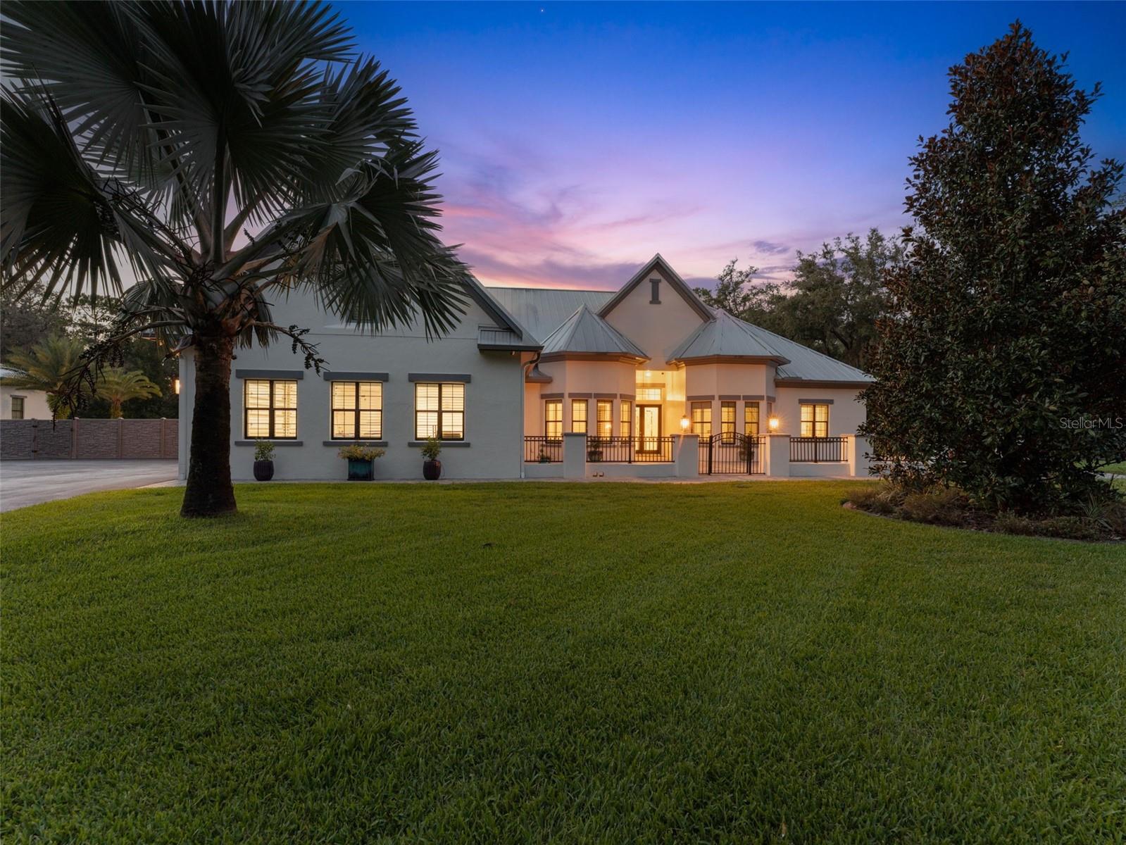 Experience modern luxury and refined living in this stunning estate, nestled on over 6 gated and fenced acres in the highly sought-after community of Odessa. Boasting 4 bedrooms, 5 bathrooms, and 5,000 sq. ft. of beautifully designed living space, this home was built in 2017 with exceptional craftsmanship and contemporary finishes. Soaring 12’ tray ceilings with 10” crown molding set the tone for the open-concept main living area, where designer LED lighting and French doors seamlessly connect the indoors to a resort-style backyard featuring a zero-entry heated saltwater pool, screened lanai, and fully equipped outdoor kitchen. Designed for both comfort and convenience, this Smart home includes in-wall iPads with Control4 Software, an audio/visual security system, NEST thermostats and smoke detectors, and a whole-house 22 KW generator. Entertain in style with a private home theatre hidden behind a secret bookcase door, complete with a 10 ft. screen, custom sound system and acoustic insulation for the ultimate movie night. The chef’s kitchen is a showstopper, featuring high-end stainless steel appliances, double ovens, a gas cooktop, two dishwashers, an oversized island, and a butler’s pantry with a library ladder and 250+ bottle wine cooler. Each spacious bedroom offers walk-in closets, wireless blinds, ensuite baths, and ample natural light, while the master suite is a true retreat with a freestanding soaking tub, dual vanities, and a glass-enclosed shower. Car enthusiasts and hobbyists will love the insulated and air conditioned 4-car attached garage, plus a detached 56x20x18 air-conditioned workshop, RV garage, or boat garage complete with 220V outlet, epoxy floors, 10k lb car lift, and a fully insulated attic. The expansive driveway can accommodate 20+ additional vehicles, making this home perfect for entertaining. Ideally located just 20 minutes from Tampa International Airport, 25 minutes from Downtown Tampa, and 35 minutes from Florida’s Gulf Coast beaches, this property offers the perfect blend of privacy and convenience. Don’t wait to build your dream home—schedule a private tour today!
