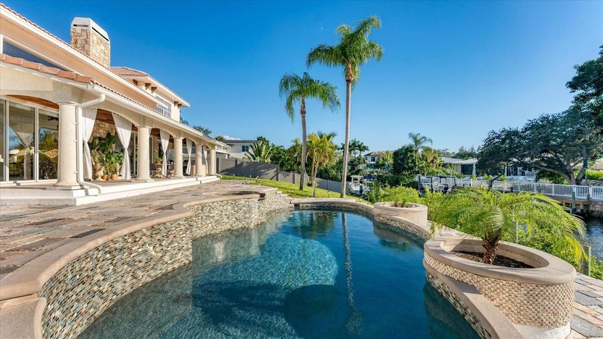 Looking for waterfront living and a boating lifestyle? Look no further! This grand residence, located in Coral Cove, provides direct access to the Intracoastal waterway, yet safely tucked away and situated on an elevated lot well above flood risk. With proximity to one of the top-rated beaches in the US – Siesta Key, this refined home offers flexible and open living spaces – indoor and out. A double-door entry opens to a grand foyer and a spacious great room with a two-story volume ceiling, fireplace, and a wall of sliding glass doors showcasing the saltwater pool and tranquil water views beyond. Extensively renovated in 2009 per public records, this home features four bedrooms and four baths with marble, granite, and Egyptian limestone surfaces throughout. Two of these are full en suites with water views; either can serve as a primary suite – one on the first floor, the other above. The first-floor suite overlooks the pool, spa, and waterway and includes a marble bath accented with onyx lighting. The second floor suite showcases bamboo flooring and a custom en suite bath with stunning Caesarstone quartz walls and flooring, LED lighting inserts, recycled glass, a jetted tub, dual gray Caesarstone vanities, and built-in closets. The gourmet kitchen is appointed with custom distressed wood and cherry cabinetry, a large Victoria Regia granite island, limestone countertops, high-end appliances, and a built-in Miele coffee system. Enjoy tranquil outdoor living and beautiful sunset views from the elevated covered lanai featuring a wood plank ceiling, a summer kitchen with granite countertops, a roll-in grill, and granite tiled decking that surrounds the pool and spa. Hop on your boat from the low-maintenance composite dock with direct access to the Intracoastal Waterway and the Gulf of Mexico. As an owner of this waterfront residence you will have access to the private Coral Cove intracoastal waterfront park and boat launch with a voluntary HOA. Surrounded by tropical landscaping and exterior lighting, this beautiful residence offers luxury finishes and thoughtful design, just minutes from Siesta Key Beach, fine dining, shopping, and the cultural amenities that make Sarasota special. Come see for yourself the extraordinary value this home offers a future owner with vision!