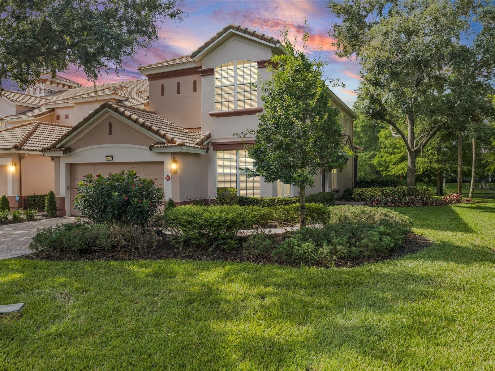 Spacious 3-bedroom, 2.5-bath end-unit townhome in the gated community of Bella Trae at ChampionsGate with stunning water views from every window. The first-floor primary suite features tray ceilings, a ceiling fan, serene pond views, and a luxurious en-suite bath with dual sinks, a soaking tub, walk-in shower, and a generous walk-in closet. Vaulted ceilings and natural light enhance the open-concept living space, flowing from the kitchen with granite countertops, stainless steel appliances, and a breakfast nook into the dining and living areas. The enclosed lanai overlooks the water, perfect for relaxing or entertaining. Additional features include a new water heater, whole-home water softener system, first-floor laundry with cabinets, a powder room, and a two-car garage. Upstairs offers a spacious loft, a second flex loft area, and two guest bedrooms with water views that share a full bathroom with dual sinks. HOA includes basic cable, internet, lawn care, and exterior maintenance. Bella Trae residents enjoy resort-style amenities including a zero-entry pool and hot tub, clubhouse, fitness center, tennis courts, putting green, billiards room, and community grills. Conveniently located near golf, restaurants, shopping, and theme parks. Schedule your private tour today