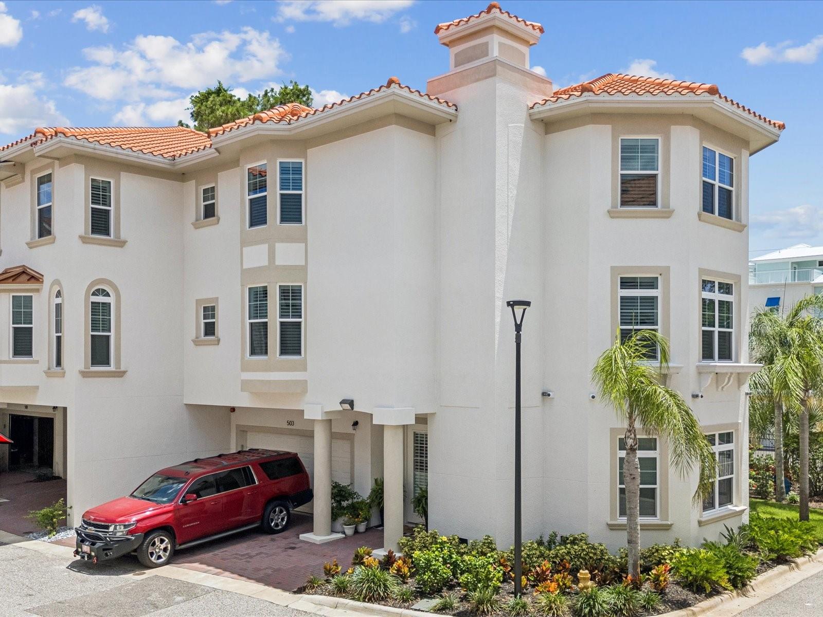 Welcome to San Ruffino, a highly sought-after gated waterfront community offering maintenance-free living, resort-style amenities, and unmatched coastal charm—just steps from vibrant Downtown Dunedin. This beautifully appointed three-story townhome was built in 2023 and blends modern luxury with timeless design. Featuring three bedrooms, 2.5 bathrooms, and over 2,300 square feet of well-appointed living space, every detail has been thoughtfully curated for comfort, style, and ease. Built with the highest standards of quality, the home offers solid block construction on all 3 floors, a private elevator as well as PGT Impact glass windows & doors, barrel tile roof and spacious private balconies. Step inside to find an open-concept floor plan with clean architectural lines, modern appointments which include wide plank hardwood floors, plantation shutters, recessed lighting, wrought iron stair rails, Quartz counters throughout with designer backsplash in the kitchen. Custom built-in closets and shelving add warmth, character and optimize functionality. Glass French doors offer privacy in the home office just off the kitchen. The gourmet kitchen is a chef’s dream—complete with updated stainless steel appliances, a center island, custom backsplash, and Quartz countertops—ideal for entertaining or quiet mornings at home.
The spacious primary suite, located on the top floor for maximum privacy, boasts a large walk-in closet with custom closets, double vanities, quartz counters and an elegant barn door fir entry into the spa like primary bathroom. Thoughtful extras like custom shelving, a separate nook, and extra storage make this home extra special. The primary bedroom also features a private balcony with a retractable screen, perfect for enjoying morning coffee with tranquil views.
Community amenities include a private gate with extra visitor parking, lush landscaping, roof maintenance, water, sewer, and trash. Relax every day at the private community pool which overlooks spectacular water views and a private kayaking pier for sunset paddles with serene water views. Enjoy life adjacent to Wilson Street Park, with direct access to the Pinellas Trail—a 47-mile biking and walking path winding through the best of Pinellas County. Just a short stroll from the heart of Downtown Dunedin, you’ll be surrounded by quaint shops, award-winning restaurants, art galleries, and a thriving cultural scene. Dunedin’s charming coastal vibe, vibrant lifestyle, and proximity to Honeymoon Island and Caladesi Island—two of the nation’s top beaches—make this location truly unbeatable.
Don’t miss your opportunity to live in luxury with low-maintenance ease in one of Florida’s most beloved communities. This Dunedin gem is truly the best of modern living with timeless beauty.