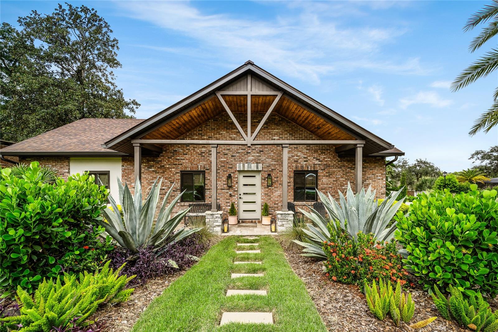 Welcome to 113 Tarrytown Trail in Longwood—an exceptional 4-bedroom, 3-bathroom custom built home boasting almost 3000 square feet of luxurious living located in established Seminole County neighborhood. Completely rebuilt in 2019 from the slab up, this home features new framing, insulation, electrical, plumbing, windows/doors HVAC and more. The exterior of the house is a testament to contemporary architectural design, with A frame wood/cedar front porch, elegant brickwork and sleek metal roof. Manicured zoysia lawn and vibrant, tropical flower beds frame the house, enhancing the curb appeal of this home located on an oversized corner lot. Inside, you’ll find rich hardwood floors throughout, level 4 finish drywall, modern lighting, and elegant architectural details including wainscoting, tray ceilings, and tongue & groove cedar accents. Off the foyer is a sitting room with floor-to-ceiling built-ins, and stunning brick wine closet with glass door and custom lighting. Across the way are french doors that open to a home office or optional 4th bedroom. The center of the home, with soaring ceilings offers an open-concept seamlessly connecting the living room to the dining room and kitchen. The chef’s kitchen features quartzite countertops, stacked cabinets with glass accents, a two-basin copper apron sink, large peninsula, subway tile backsplash, bronze range hood and a walk-in pantry with solid wood shelving. The family room boasts angled ceilings, a sleek fireplace flanked with built-in shelving, TV niche and sliders that overlook private screened lanai. The luxurious primary suite (on main floor) offers a serene escape with its spacious layout, fireplace and minimal design. Custom built-in shelving/vanity and roman shades complete the space. This suite offers 2 closets, one walk-in and both with custom closet systems. The Spa-like primary bathroom features oversized two-person shower, clawfoot tub, glass door water closet, quartzite countertops and tile from floor to ceiling. Two additional bathrooms are equally well-appointed with tile wainscoting, custom vanities, exceptional lighting and high-end finishes. Bedroom 2 downstairs and upstairs above the garage enjoy a large guest bedroom and flexible loft space perfect for office, studio or workout space. Brick path walks you through the mudroom to your 2 car oversized garage with tons of built-in storage and walk-in storage closet. From there you can access the 3rd garage/carport. Custom barn door elegantly camouflages the unique and spacious laundry room. Imagine stepping into a serene retreat right in your own backyard. The back patio is a harmonious blend of design and comfort and the perfect for entertaining. The back lanai features a vaulted tongue & groove cedar ceiling, custom lighting and opens to a fully screened enclosure. The custom outdoor kitchen includes a Napoleon grill, burner, granite countertops, and sink. From there you have access to a walk-in finished storage closet, great for storing outdoor kitchen supplies, cushions, games, garden utensils and more. Mature landscaping surrounds this paver courtyard offering a private place to relax and unwind!