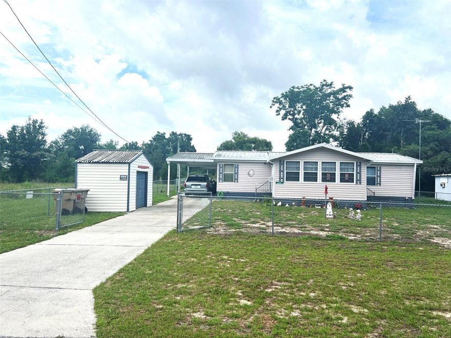 Looking for freedom, privacy, and value without HOA fees or deed restrictions? This well-maintained 3-bedroom, 2-bath home offers a rare opportunity to enjoy true Florida living with room for your boat, RV, work trailer, pets, hobbies, and more. Fully fenced in the front, side, and back yards, this property provides security, flexibility, and peaceful surroundings that are becoming harder to find.

One of the property’s best features is the incredible backyard setting backing up to hundreds of acres of privately owned land, creating beautiful open pasture views and added privacy with no close rear neighbors. Enjoy relaxing mornings or evening sunsets from the large backyard deck overlooking the neighboring countryside.

Inside, the split-bedroom floor plan offers comfortable living with a spacious living room, dining area, volume ceilings, ceiling fans, and an inside laundry room. The primary suite includes a walk-in closet and private bath, while the light-filled enclosed front porch with ceiling fan and two exit doors adds flexible living space perfect for relaxing or entertaining.

The property also includes outstanding storage and utility features with two separate sheds. The front shed houses the irrigation well, separate house well, and water softener system. The rear workshop/storage shed includes electric, window A/C, very dry storage space, and a durable metal roof.

Mature landscaping, oak trees, and fruit trees complete the property, while nearby lake access and boat ramps make this an ideal location for outdoor enthusiasts. A rare combination of privacy, usable land, storage, and freedom with no HOA restrictions.