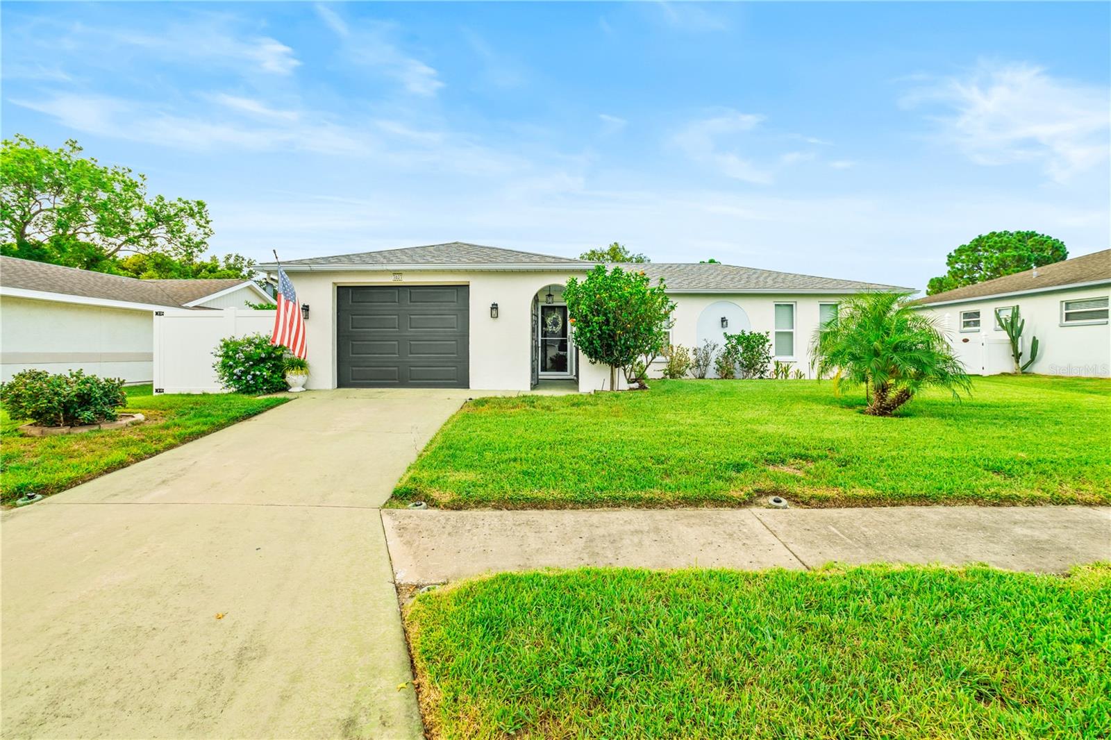 WELCOME TO YOUR DREAM FLORIDA OASIS! Nestled in a quiet, low-traffic neighborhood, this beautifully maintained and fully furnished home is the perfect blend of comfort, convenience, and charm. From the moment you step inside, you’ll notice the elegant porcelain tile flooring throughout, a bright and inviting open floor plan. This home does come partially furnished. The updated kitchen is a standout feature with its 10-foot granite island, modern cabinets, recessed lighting, and a nearly new microwave. Both bathrooms have been thoughtfully remodeled with ceramic tile in 2022, adding a touch of luxury. Step outside to enjoy the Florida lifestyle on your enclosed lanai with privacy shades or host gatherings on the paver patio surrounded by lush, vibrant landscaping that includes a pineapple tree, multiple hibiscus varieties, roses, lilies, and butterfly-attracting milkweed. The fully fenced yard and gated entry add privacy, while the 1-car garage with a new door, opener, washer, and dryer offers practical convenience. A/C unit is only 3 years old. Fresh paint added in 2021. Located just minutes from shopping, dining, Publix, Walmart, Sims Park with a splash pad, and several golf courses, this home also offers easy access to major roads. Only 45 minutes to Tampa International Airport and 30 minutes to the stunning Gulf beaches like Sunset Beach, Honeymoon Island, Green Key Bay and Downtown Dunedin. With optional community pool access and proximity to Downtown New Port Richey’s vibrant festivals and events, this home invites you to settle in, relax, and enjoy everything Florida living has to offer. Don’t miss this opportunity to own a move-in-ready retreat where every detail has been thoughtfully designed for everyday enjoyment.