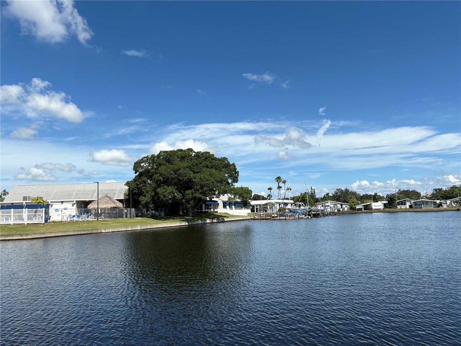 This waterfront home is on a corner lot and has 2 bedrooms/2 bathrooms, a dock and an open porch. The windows, laminate floors, mini split A/C, carport, and vapor barrier are all new in 2024-2025. There are solid surface countertops in the kitchen and bathroom,
Price includes share for the lot and ownership in the co-op. Home is located in Americana Cove, a 55+, resident owned, waterfront community only 10 minutes from downtown St. Pete, 20 minutes from two airports, and 25 minutes to Gulf beaches. Low monthly fee of $380 includes 24 hour manned gate, private streets, water/sewer, lawn mowing/edging, trash pick up twice weekly and all amenities including heated pool, shuffleboard, bocce ball, two boat ramps and kayak launch. And many clubs and activities to get involved in.