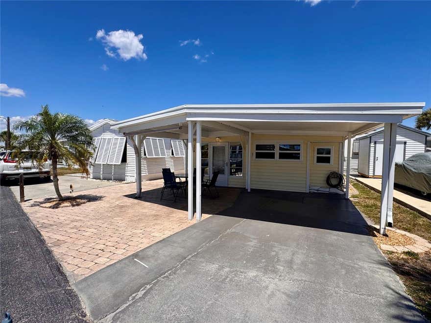 Welcome to the "Coastal Cottage Retreat" - a meticulously updated, TURNKEY FURNISHED residence in the gated community of Holiday Travel Park, where YOU OWN THE LAND! Golf cart and RV friendly, this charming home blends comfort, style, and an unbeatable Florida lifestyle. A standout feature is the rare 21’ x 21’ covered front patio, offering an incredible shaded outdoor living space—perfect for morning coffee, evening cocktails, and soaking in those stunning Florida sunsets. Inside, this move-in ready 2-bedroom, 2-bathroom home (588 sq ft) has been thoughtfully upgraded with a new metal roof (2023), A/C (2021), hot water heater (2023), newer double-pane windows on the front and right side, plantation shutters in the dining room and both bedrooms and new carpet in the living room. The kitchen is both functional and stylish, featuring granite countertops and a modern stone tile backsplash. You’ll also appreciate the abundant storage, interior laundry room, and a shed/workshop with electric—perfect for hobbies or extra space. On city water and city sewer! Holiday Travel Park offers low HOA fees ($140/month) that includes water/sewer, a heated community pool, lawn maintenance, an active clubhouse with social events, pool tables, indoor pickleball and a scenic kayak launch with a peaceful freshwater lake setting. RV/boat storage onsite for $100 annually. Located less than 10 minutes from Manasota Key, you’ll enjoy easy access to beautiful Gulf beaches including Englewood Beach, Stump Pass State Park, Middle Beach, and Manasota Beach. Pet-friendly—one pet allowed up to 40 lbs. Don’t miss your chance to own this slice of coastal charm—schedule your showing today and start living the Florida lifestyle you’ve been dreaming of!