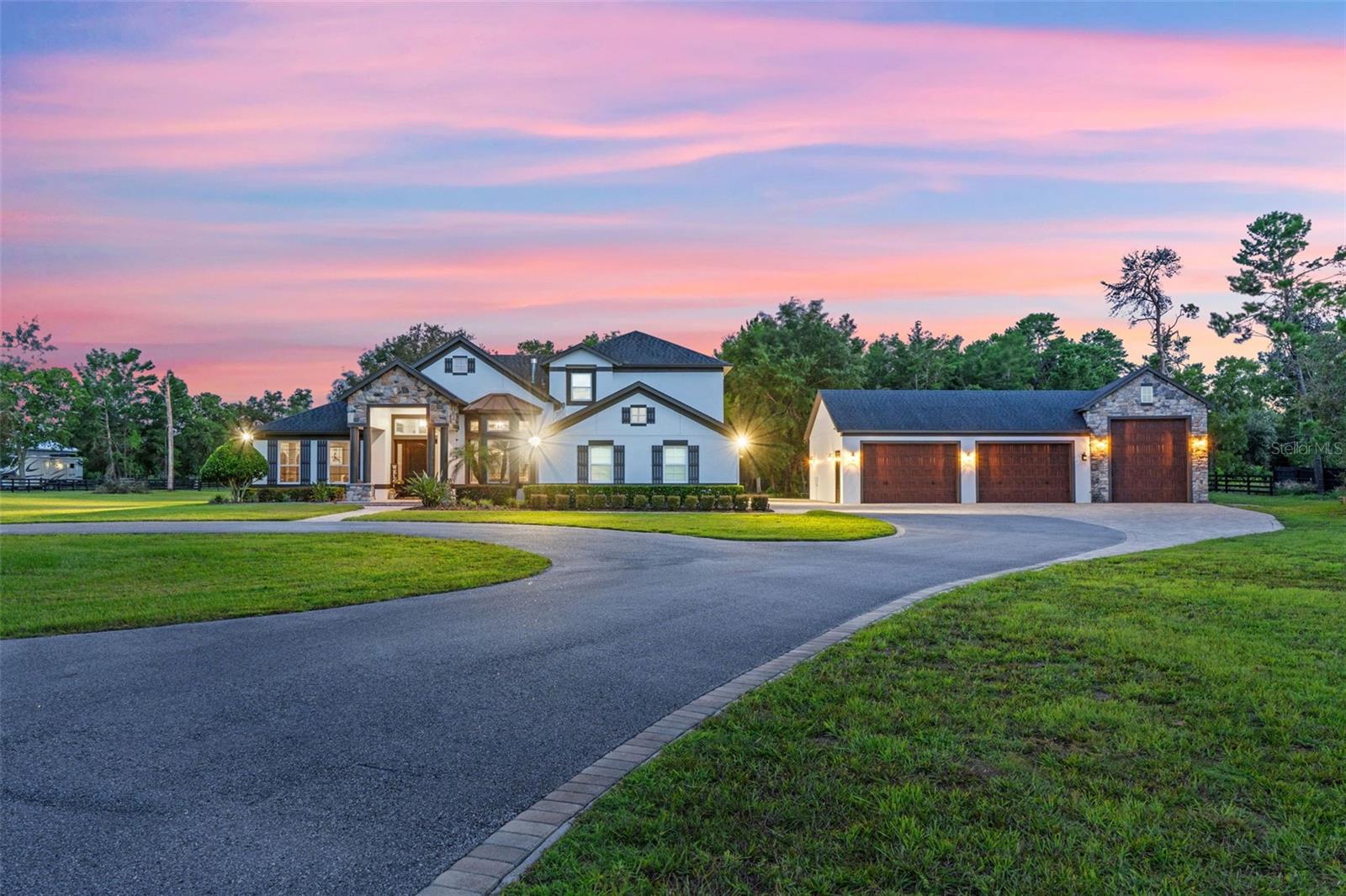 EXTREMELY RARE OPPORTUNITY to own a fully custom CONTEMPORARY DREAM ESTATE on 5 private “high and dry” acres in the heart of Seminole County, FL!!! Consisting of both a 4000 square foot executive style pool home and a 2200+ square foot detached multi vehicle garage/workshop, this HOMESTEAD PARADISE combines the comforts and style of MODERN LUXURY LIVING with all the freedom and outdoor space you need to enjoy the LIFESTYLE OF YOUR CHOOSING. Arrive at the property and pass through the paver front patio into a home full of warmth, modern elegance, and UPGRADES EVERYWHERE. Enter into an expansive OPEN CONCEPT great room featuring cathedral style 13+ foot high TRAY CEILINGS equipped with dedicated LED up-lighting and crown molding. Immediately to your left is a barn door bonus room that has been curated into a custom wet bar/entertainment room with built-in bottle storage and lounge tables. Multiple living areas are highlighted by natural stone accents and two propane fireplaces creating separate vignettes depending on your lounging and entertaining needs. The GOURMET KITCHEN is a chef's dream! Featuring an enormous eat-in island, upgraded appliances, farmhouse sink, propane cooktop with pot filler and custom hood, level 4+ granite counters, hardwood cabinets, additional dining area, and barn door pantry. The SPLIT BEDROOM LAYOUT provides enhanced privacy for the oversized owner's retreat. The master bedroom features tray ceilings, a private propane fireplace, French door lanai access, and a large walk-in closet fully equipped with built-in organizers and shelving. The master bath creates a SPA-LIKE EXPERIENCE with a massive tile shower with dual rainfall shower heads, Victoria and Albert claw foot bathtub, and oversized dual sink vanity with underlit LEDs. Additionally, the first floor contains two auxiliary bedrooms both with walk-in closets, one private full bath with pool access, a full guest bath, laundry room, and 3 car attached garage. The second floor completes the floorplan with a large loft area, additional full bathroom, a fourth bedroom, and a fully equipped theater room with built-in projector and "starlight" fiber optic lighting. Stepping through the pocket sliding doors onto the rear lanai you will experience a true POOLSIDE OASIS. The oversized lanai has ample space for both lounging and dining and features a massive outdoor kitchen with two hard lined propane grills and extended bar top dining space. The 39 foot long HEATED SALTWATER POOL is loaded with upgrades including: a NATURAL STONE WATERFALL, tanning ledge, built-in stone table, heated jacuzzi, propane firepit, and multi-color changing LED lighting. Beyond the pool are horse pastures and a covered feeding area. The property is zoned A-1 so bring your animals! The detached garage is massive and extremely versatile. The 2200 sq. foot space can accommodate vehicles of different sizes including cars, boats, RVs, tractors etc. Additional features of the garage include: 13-16 foot custom ceilings, a half bathroom, 50+ recessed can lights, a polished concrete floor, and an oversized rear paver patio. Conveniently located near ample shopping, dining and several major commutable highways, this property provides a rare blend of both daily modern comforts and expansive outdoor living and privacy. A true UNICORN on the market; this home is expected to sell fast! Secure your opportunity to live the DREAM FLORIDA LIFESTYLE and book your private showing TODAY!!