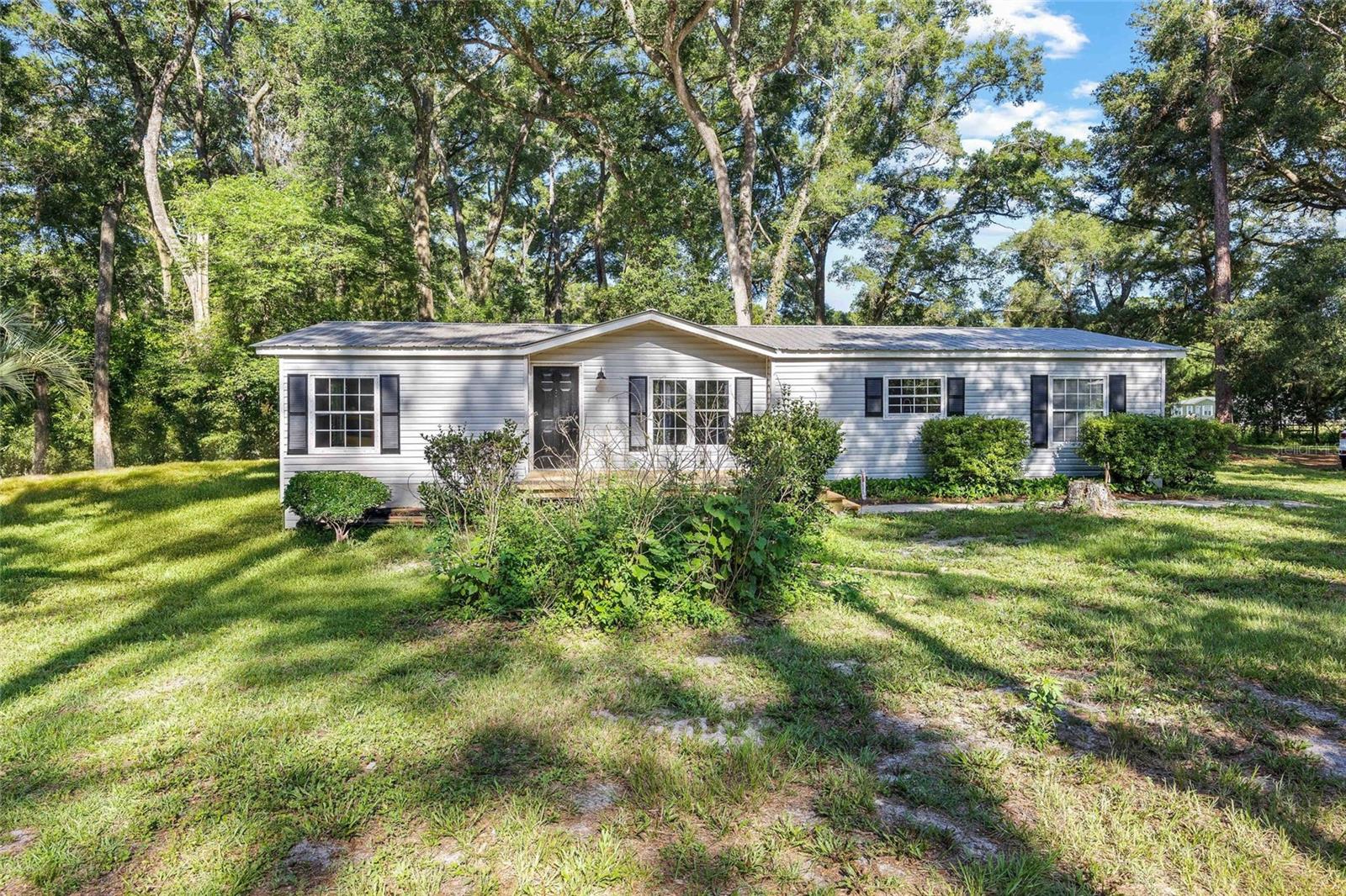 Absolutely Breathtaking 10-Acre Mini Farm - from the moment you turn onto the oak-lined lane, you’ll feel the magic of this special property. Set on 10 beautiful acres, the land is well-designed for animals with a barn, pens, chicken coop, and open pasture. A screened-in section of the barn provides versatile space for storage, hobbies, or entertaining. The inviting 3-bedroom, 2-bath home features brand-new appliances, a wood-burning fireplace, and a spacious new front porch—perfect for taking in the peaceful farm views.
The grounds are dotted with plants and trees that bloom year-round from camellias, Japanese magnolias, and an array of fruit trees including figs, pears, and multiple citrus varieties. With a mostly fenced perimeter and gated entry, you’ll enjoy privacy, security, and room to roam—just 5 minutes from Archer, 10 minutes to Newberry, and 20 minutes from Gainesville. This is country living at its best, with town conveniences just a short drive away. Enjoy the best of country living without sacrificing connectivity—this home is equipped with AT&T high-speed internet. New electrical panel (2024), septic pumped (2022), HVAC (2022) and the well was replaced (2022).