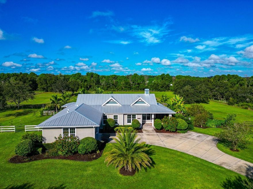 One or more photo(s) has been virtually staged. Just east of I-75 in Sarasota County, you’ll discover an enchanting home nestled on nearly 5 acres. It provides a peaceful escape that feels wonderfully remote, yet it's just a quick drive to town, where endless conveniences await you. A well-regarded custom builder constructed this home for comfort & relaxation, featuring 2-3 bedrooms, two bathrooms, & a bonus flex room. Experience this stunning residence, which has over 2,000 square feet of space, where every corner reflects thoughtful upgrades that embody a warm & inviting ambiance. You'll be greeted by impressive 10 to 14-foot beamed ceilings & warm shiplap walls that enhance the welcoming atmosphere. The beautiful, engineered hardwood floors complement elegant wood cabinetry, all crafted w/care & boasting distinctive honed quartz surfaces w/chiseled edges. Additionally, designer lighting & exquisite handcrafted built-ins elevate the overall aesthetic. Solid core doors add an extra touch of quality & durability. The great room boasts an inviting layout that seamlessly blends living & dining areas, w/a stunning stone gas fireplace serving as an eye-catching centerpiece. Open to a masterfully designed kitchen tailored for culinary enthusiasts. Key features of this stylish space include a 5-burner gas range w/a convection oven, fitted w/extras, & Pennville distressed pecan wood cabinetry w/soft-close drawers & 42-inch upper cabinets. It also offers task lighting, a stone backsplash, & a spacious walk-in pantry. Additionally, there is a center island that has more storage, an apron sink, wine refrigeration, & a serving nook designed for your unique furniture piece. Custom sustainable wood barn doors provide privacy for the guest bedroom, which currently serves a dual purpose as a study w/cabinetry instead of a built-in closet. On this side of the home, a fully-equipped laundry room, a second bedroom, & a bath showcase the same high-end upgrades & finishes found throughout, making the space inviting & impressive. The Owner’s Suite is thoughtfully located for maximum privacy, w/breathtaking views of the tranquil pool & the expansive grounds surrounding it. Complete w/a generous dressing room w/closet built-ins & a flexible bonus room—perfect for whatever your heart desires! Discover your serene escape in the en suite oasis, w/a designer MTI brand bathtub offering hydrotherapy, a separate massive Roman shower w/a tiled surround, dual sinks, & a water closet. What would a picturesque countryside retreat be without an inviting outdoor screened porch that wraps around, offering sweeping views of the breathtaking sunrises & sunsets each day? Appreciate the beauty of nature from the covered & screened areas, as wildlife flourishes nearby. Relax by the stunning pool or pamper yourself in the luxurious spa, recently installed by Umbare Pools in 2023 for your ultimate enjoyment. Gather around the fire pit, under a starlit sky. Don't miss the meditation garden, which is sure to attract an abundance of butterflies. Imagine fulfilling your dream by building a state-of-the-art barn & bringing your horses to explore the expansive, fenced, and cross-fenced acreage. This highly customized home offers an impressive range of features that cannot all be listed, making it an appealing choice for anyone seeking a spacious country retreat. An estate in Deer Hammock offers an excellent opportunity w/perfect balance, enhanced by deed restrictions that maintain the community's aesthetic appeal & property values.