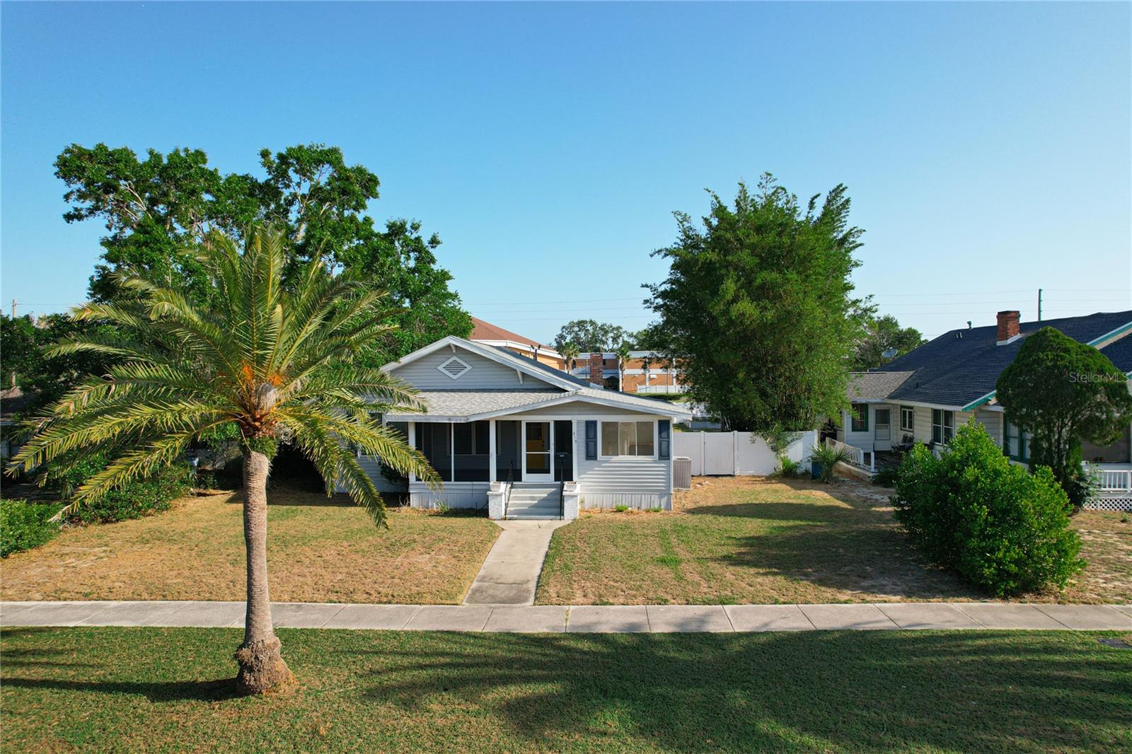 Located in the heart of Lake Wales' Historic District, this beautifully restored 1920s Craftsman-style home blends timeless character with thoughtful modern updates. From the moment you step onto the welcoming screened front porch—complete with paned windows and a classic Craftsman-style door—you'll be charmed by original details like gleaming hardwood floors, soaring ceilings, and elegant picture rail molding. The inviting living room centers around a classic brick wood-burning fireplace, while the formal dining room is accented by iconic square, tapered columns. The updated kitchen features subway tile backsplash, stone countertops, a farmhouse sink, solid wood cabinetry, stainless steel appliances (including a gas range), and a spacious walk-in pantry. The generous primary suite offers a private retreat with an en suite bath featuring a tiled walk-in shower and pedestal sink. The second bedroom is comfortably sized with ample closet space, while the third bedroom—split from the others—offers built-ins, making it ideal for guests or a home office. A flexible bonus room provides even more space for a den, study, or creative studio. Step outside to a fully fenced backyard oasis, complete with a covered brick patio shaded by mature bamboo—perfect for quiet mornings or weekend entertaining. An additional covered patio offers extra storage or flex space. Alley access leads to a large rear parking pad, and a spacious shed secured with hurricane straps adds practical storage. Recent updates include a new roof (2023) and upgraded HVAC system (2016). With sidewalks just steps away from Lake Wailes and downtown shops and dining, this home offers the perfect blend of historic charm and everyday convenience. Don’t miss this rare opportunity—schedule your private showing today!