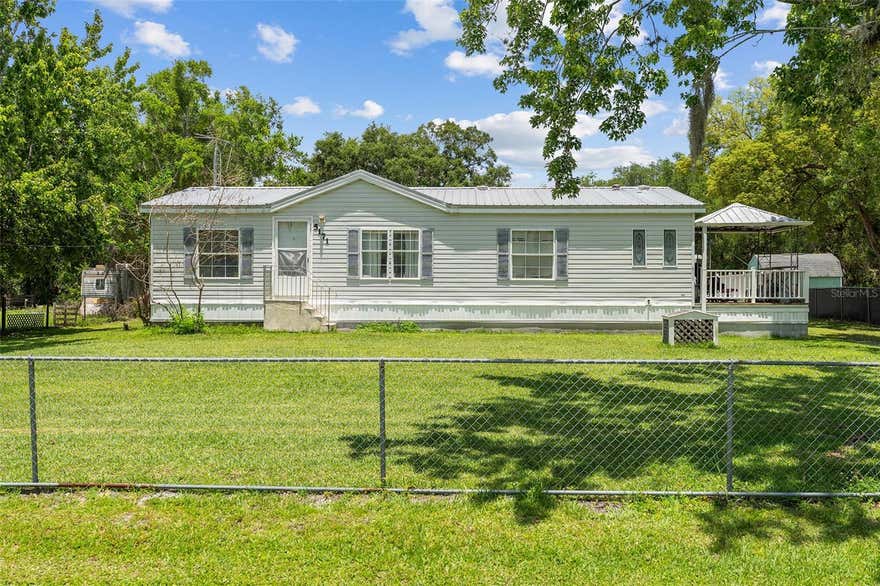 Welcome home to this charming 3-bedroom, 2-bath manufactured home situated on a spacious half-acre lot in a quiet and peaceful neighborhood. Step inside to discover an open-concept floor plan featuring laminate flooring throughout and a kitchen equipped with stainless steel appliances, making it perfect for everyday living and entertaining. Enjoy the outdoors from the expansive side and rear porch that nearly wraps around the entire home—ideal for family gatherings, weekend barbecues, or simply relaxing on cool Florida evenings. A storage shed in the backyard provides plenty of space for tools, equipment, and all your outdoor toys. Conveniently located just off Narcoossee Road, this property offers easy access to Lake Nona Medical City, Orlando International Airport, Disney attractions, beautiful beaches, shopping, dining, and more. Experience the perfect combination of peaceful country living and modern convenience!